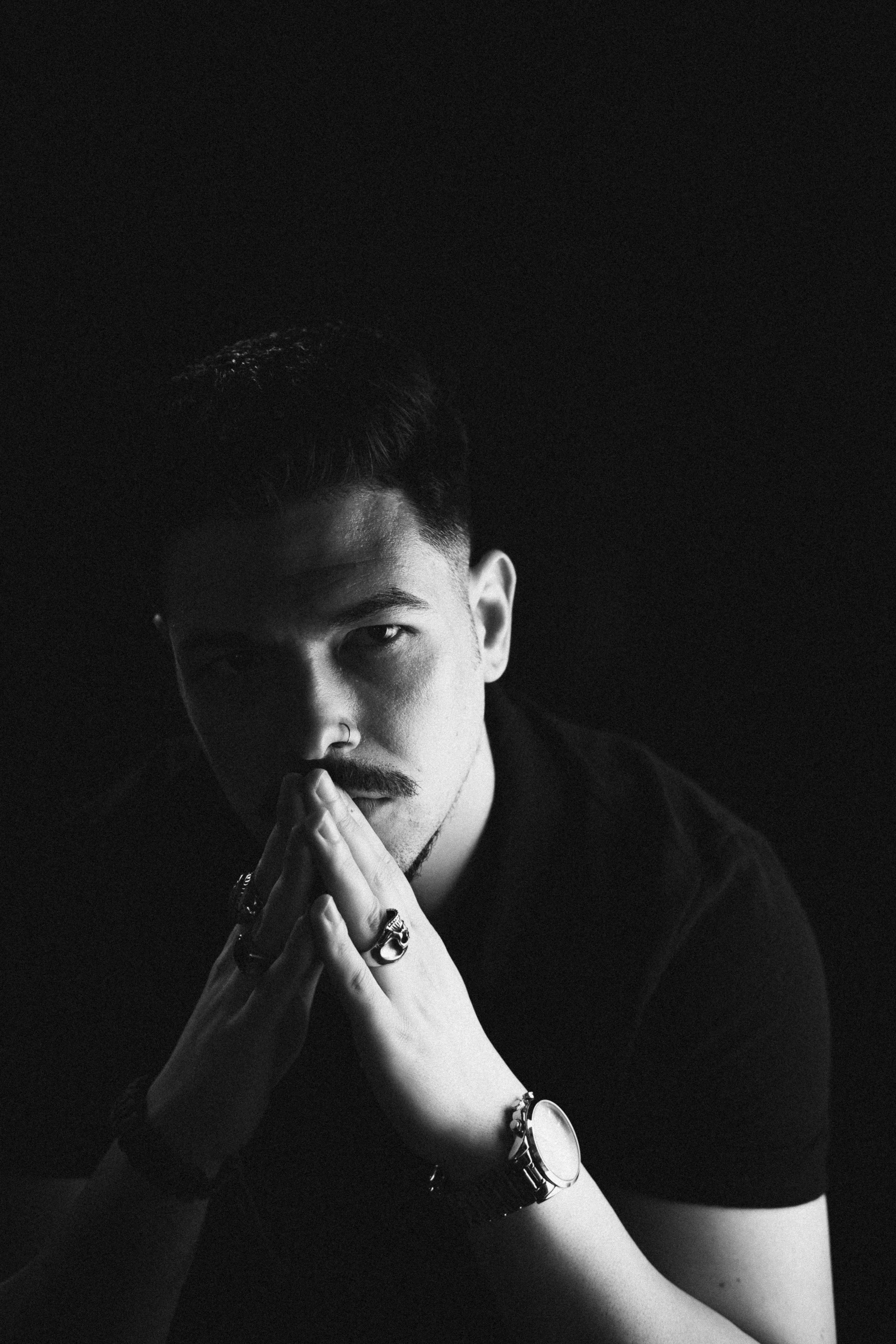 Black and white self-portrait of João Marques with a contemplative expression, hands clasped under chin.
