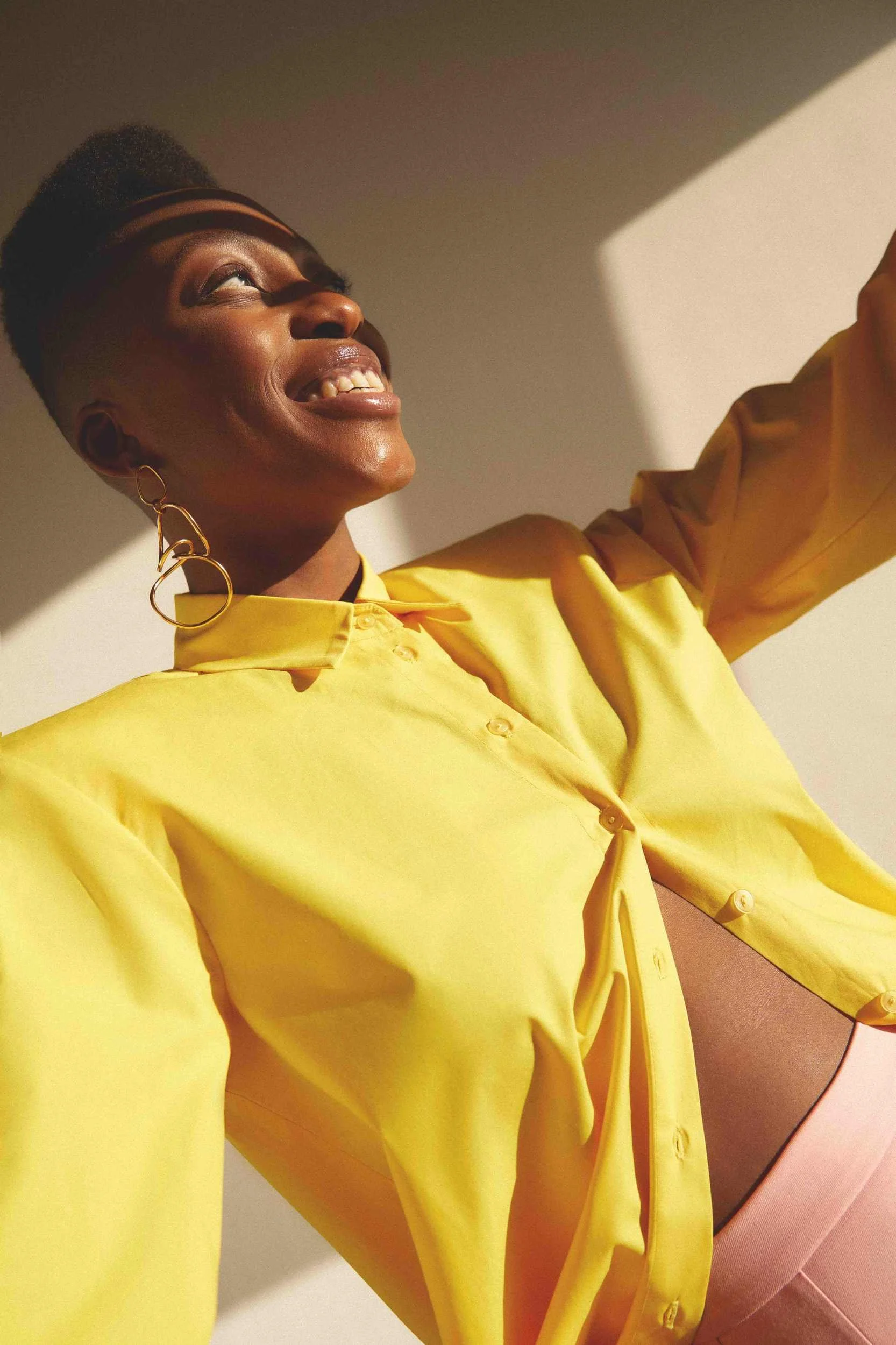 Yellow shirt with hoop earrings, laughing in sunlight