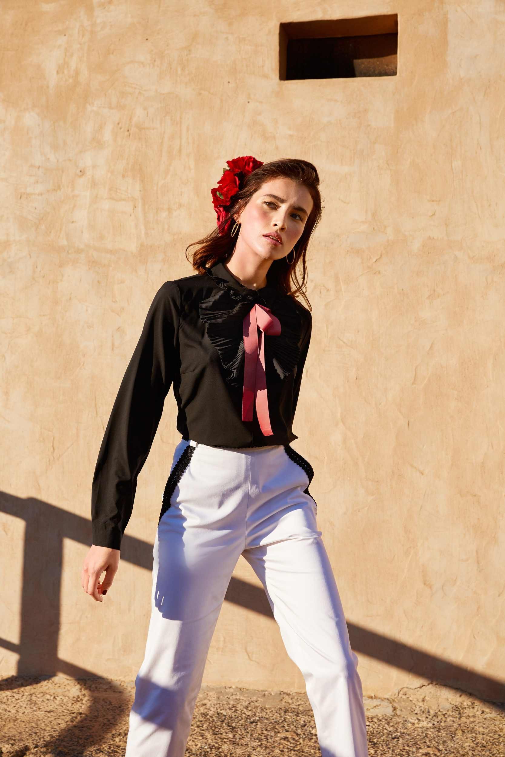 Black blouse with a pink ribbon and white trousers in hard sunlight