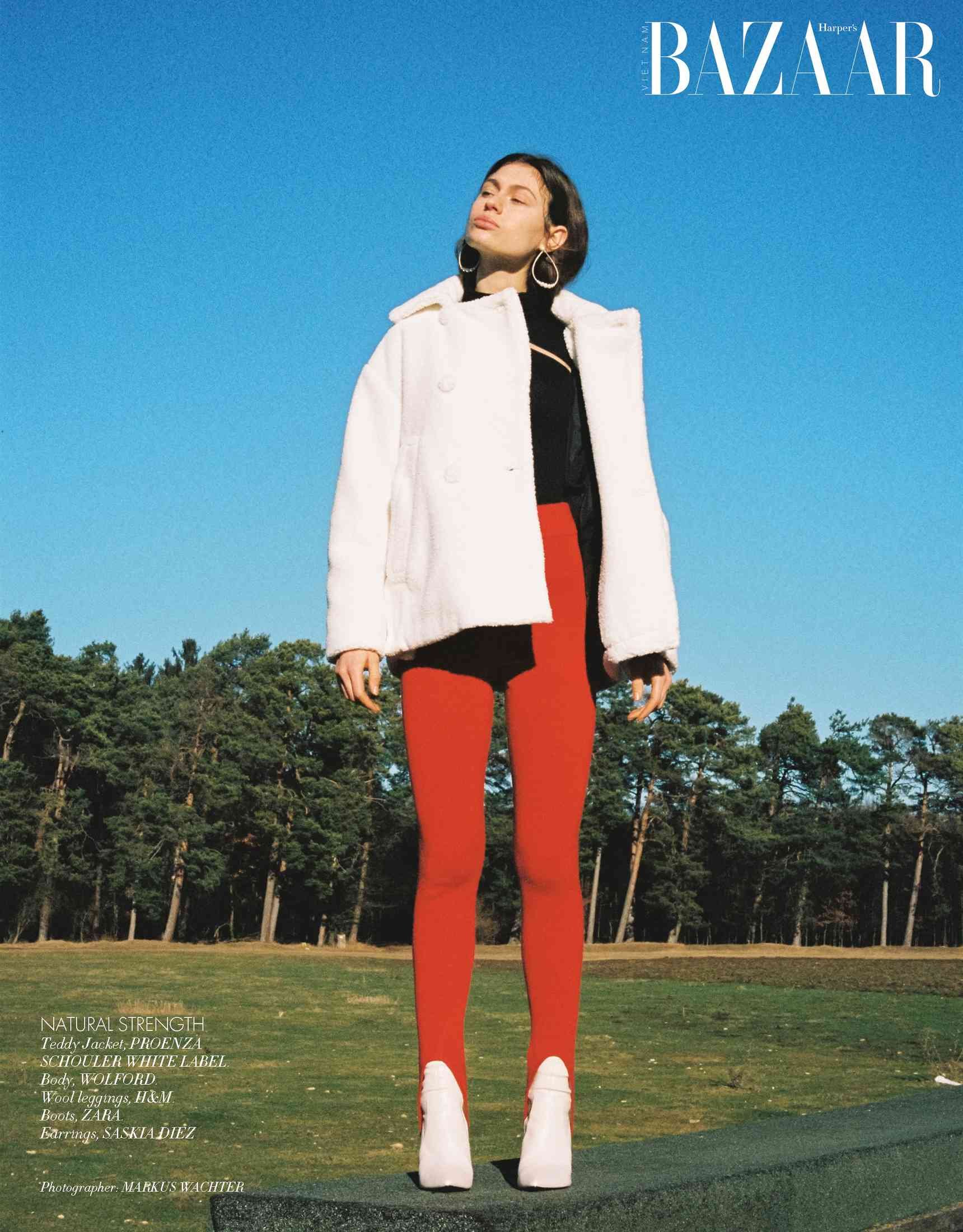 Harper's Bazaar Vietnam editorial: white coat with red trousers standing on a stone wall