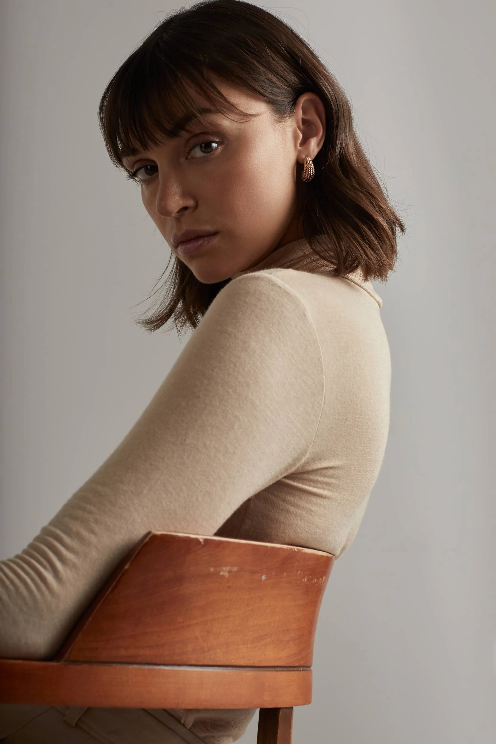 Jewellery campaign for Sian Design: beige knit top on a wooden chair, seen from behind