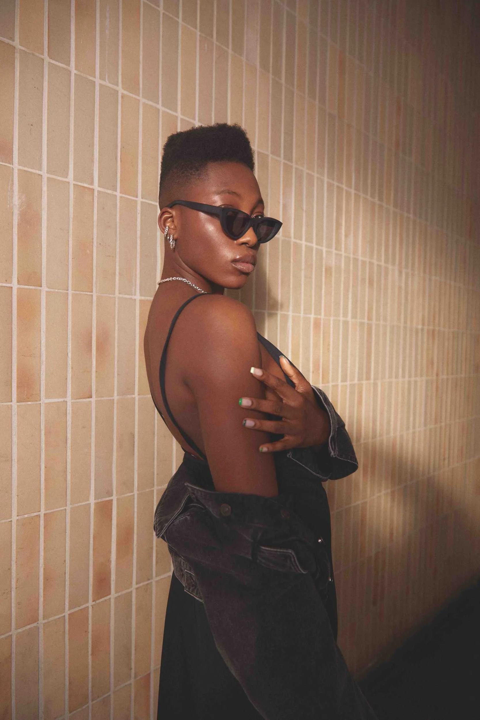 Portrait with sunglasses in front of a tiled wall, side light