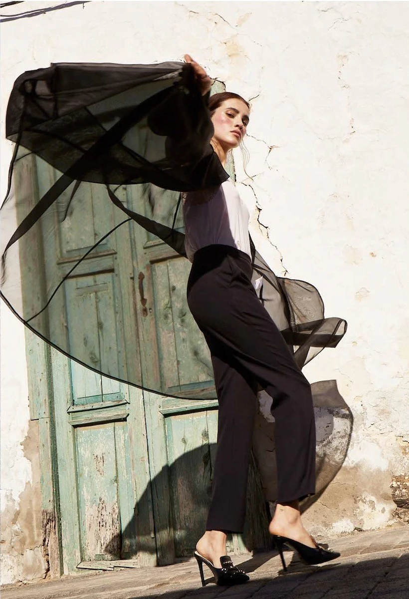 Black sheer scarf caught in the wind in front of a green door