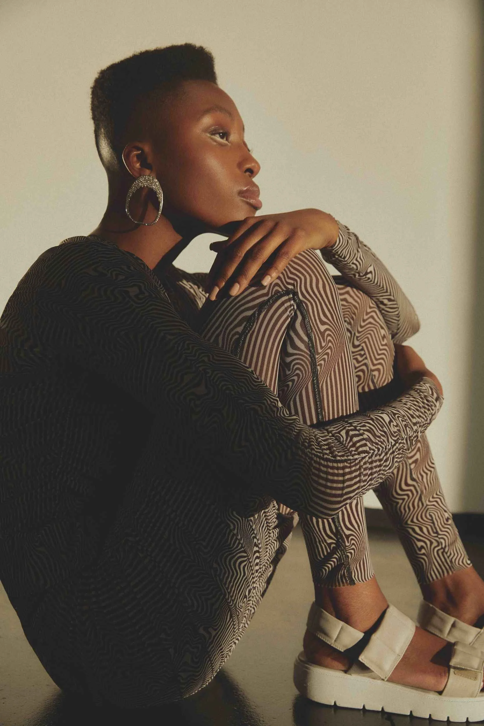 Black knit and striped trousers, seated on the floor