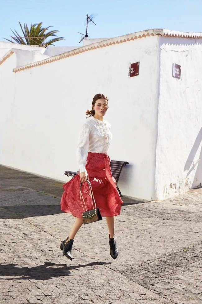 White blouse and red skirt walking along a village street