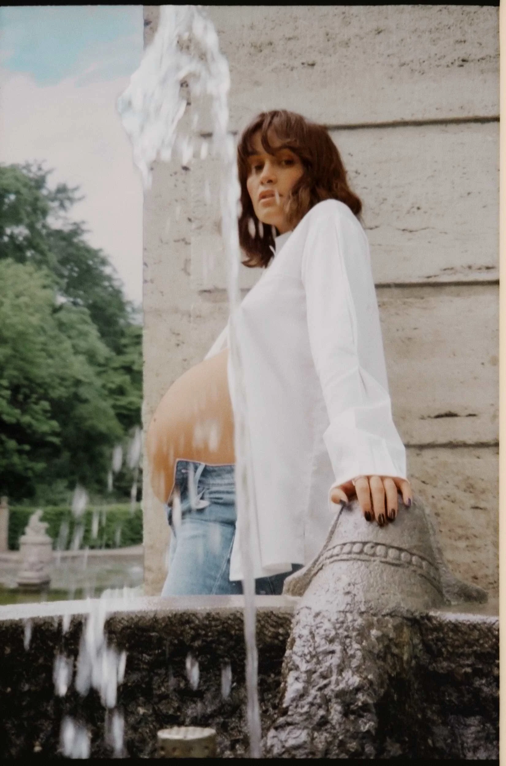 Mogli in a white shirt at a fountain