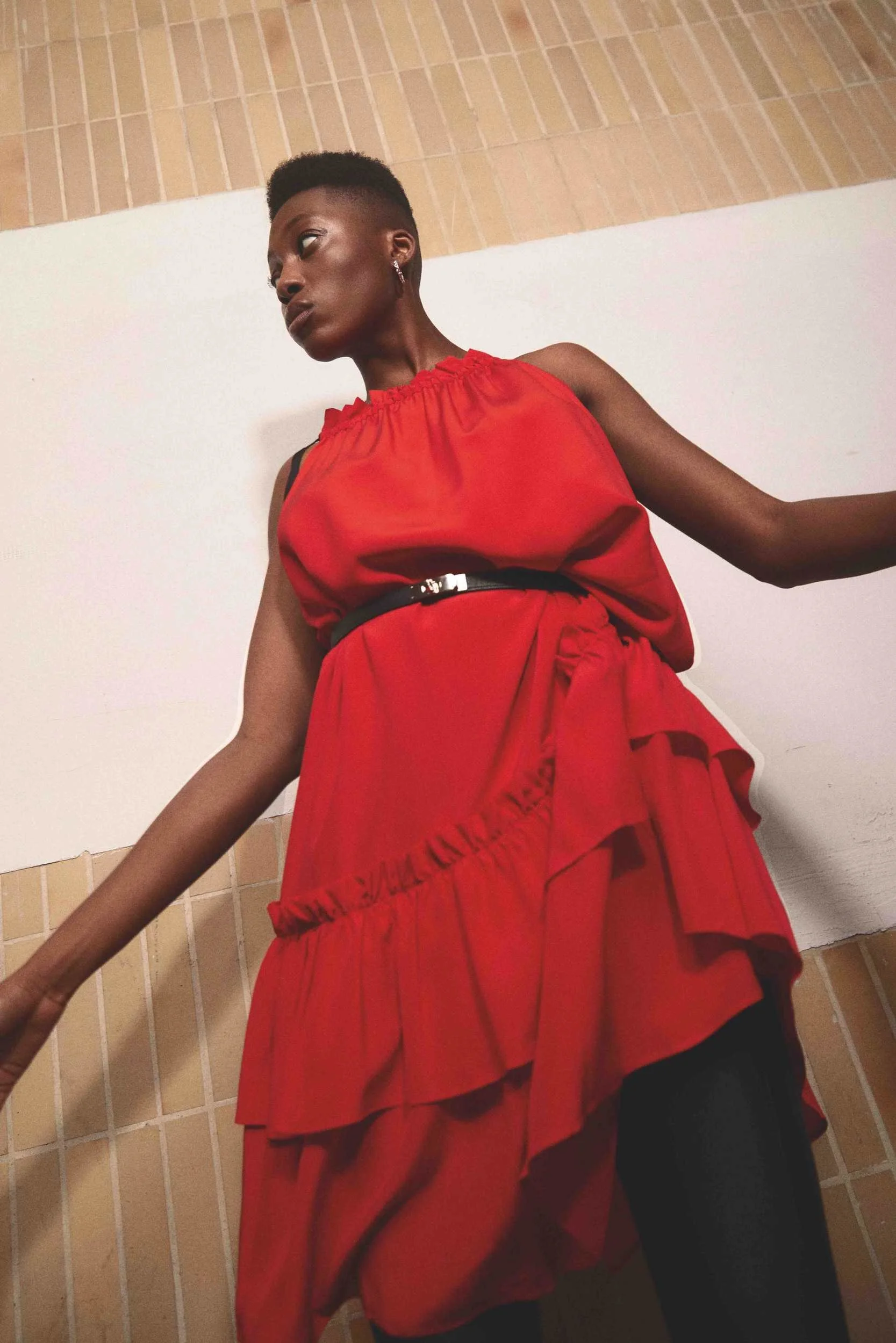 Red ruffled dress against a tiled wall in hard sunlight