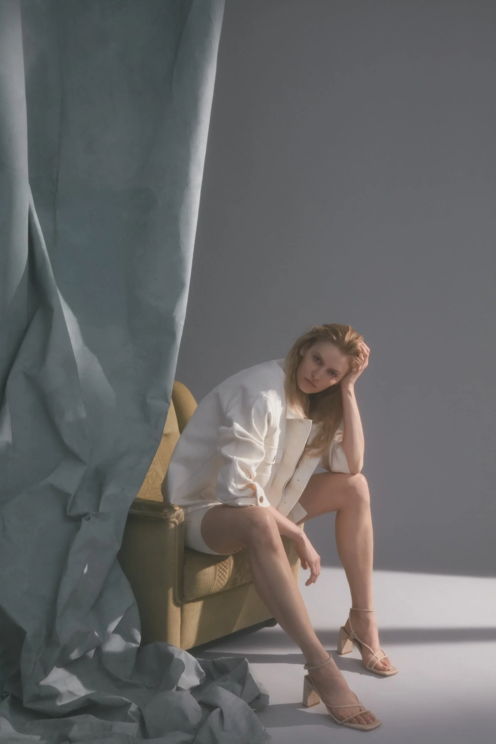 Denim editorial for Latest Magazine: white shirt, seated on a chair by a curtain