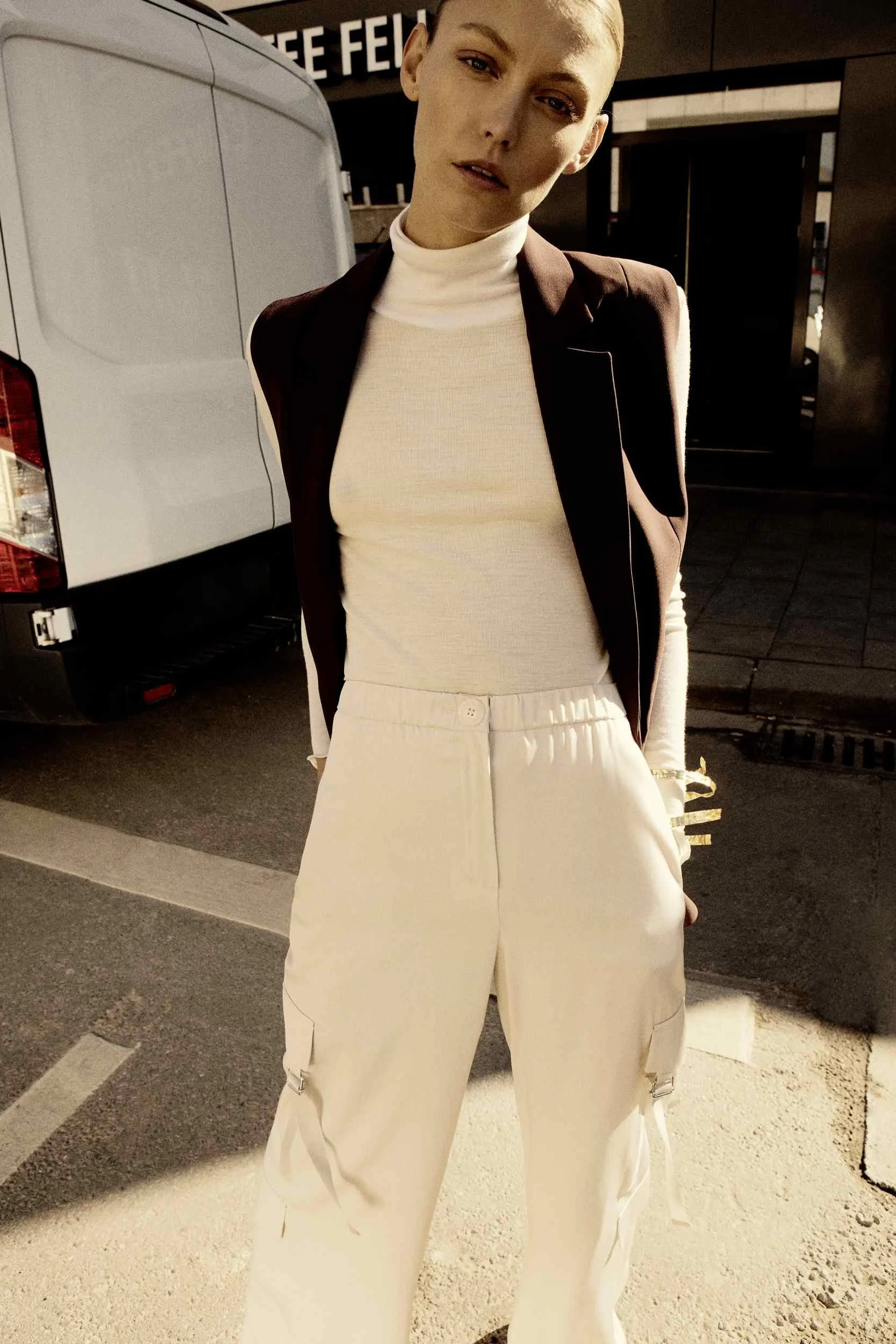 White turtleneck and black blazer in front of a delivery van