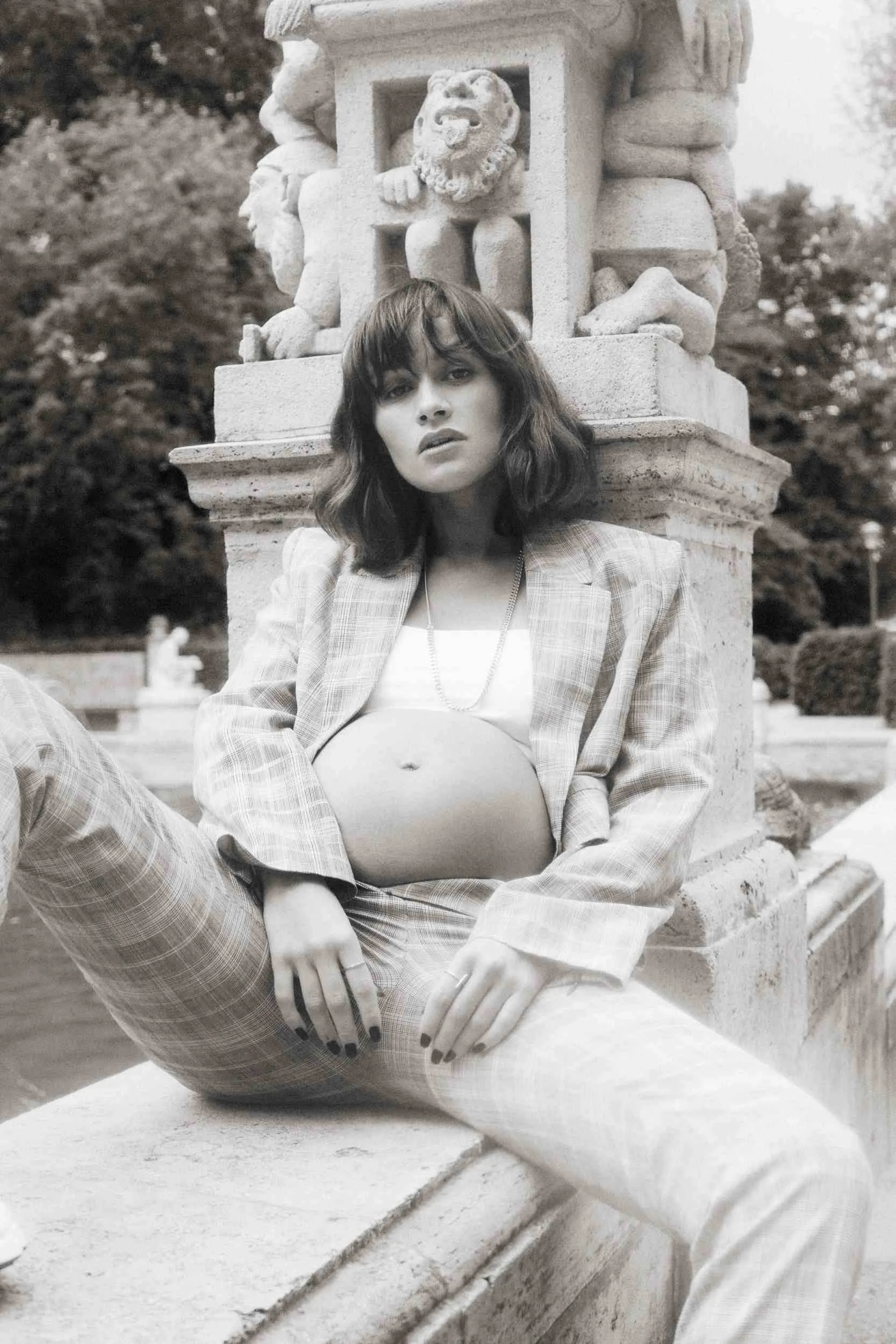 Mogli seated on a balustrade in white jeans, black and white
