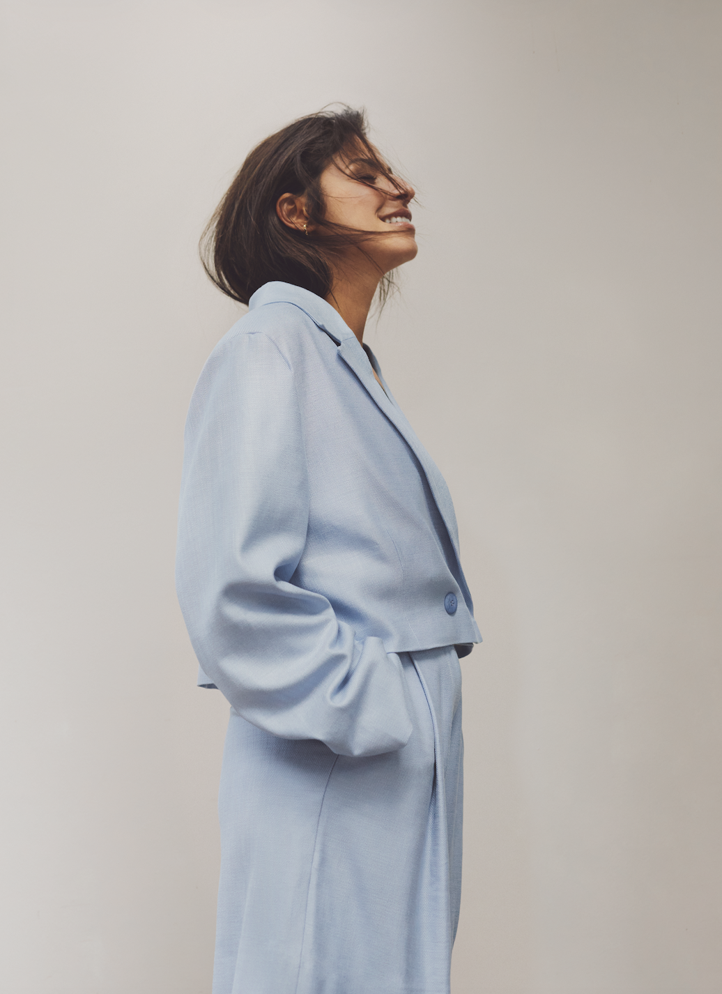 Profile portrait laughing in a light blue cropped blazer and matching wide trousers