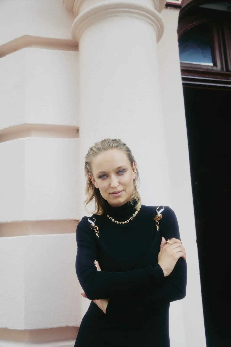 Portrait of Caro Cult in a black turtleneck beside a column