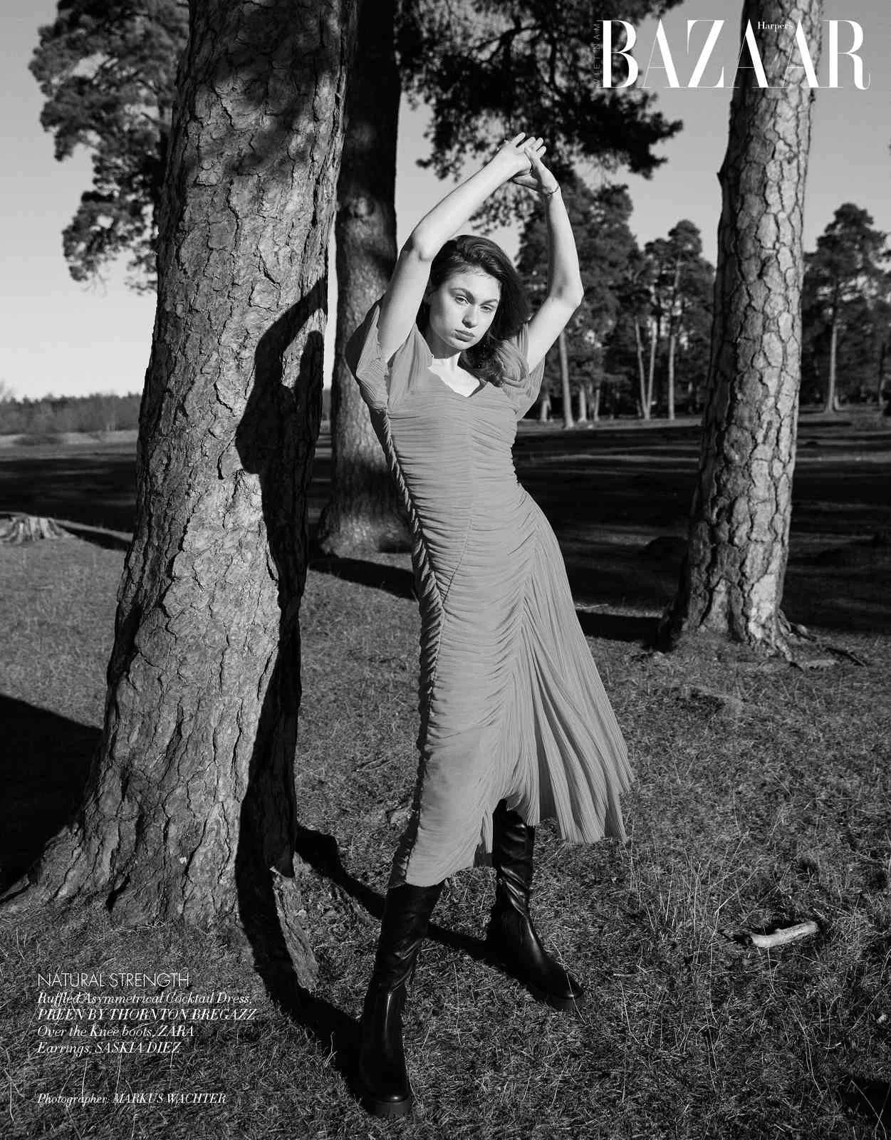 Harper's Bazaar Vietnam editorial: pleated dress, model stretching against a pine tree, black and white