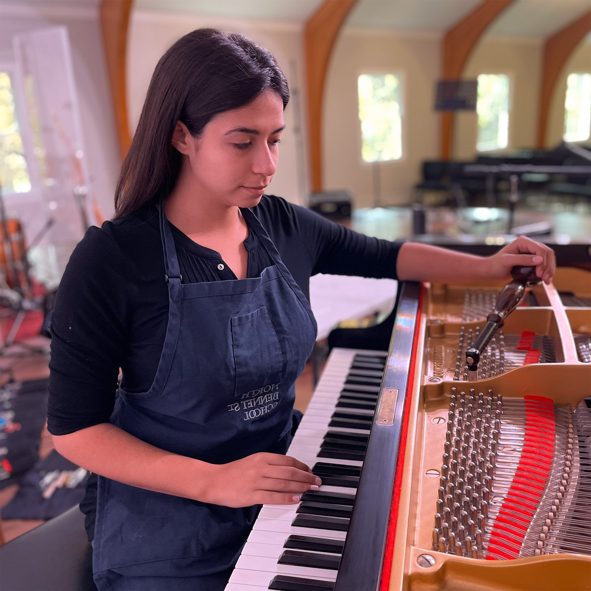 Sofia de la Peña, piano technician in Northern Virginia working at a grand piano.