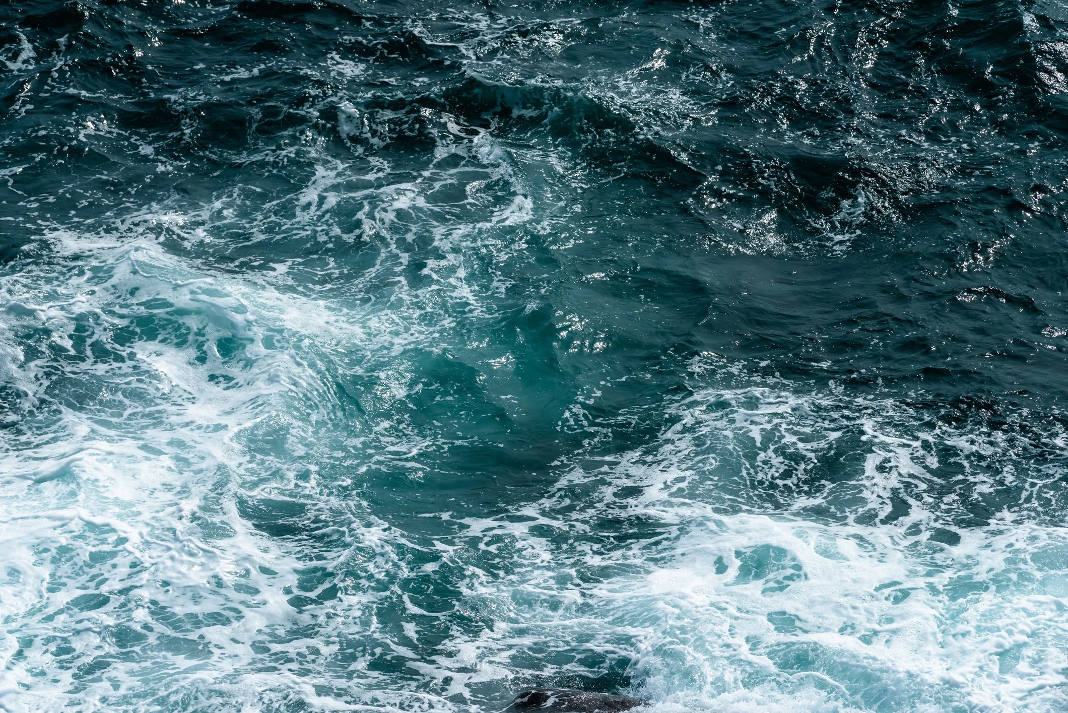 Photo of the ocean showing deep blue water with white foam and waves.