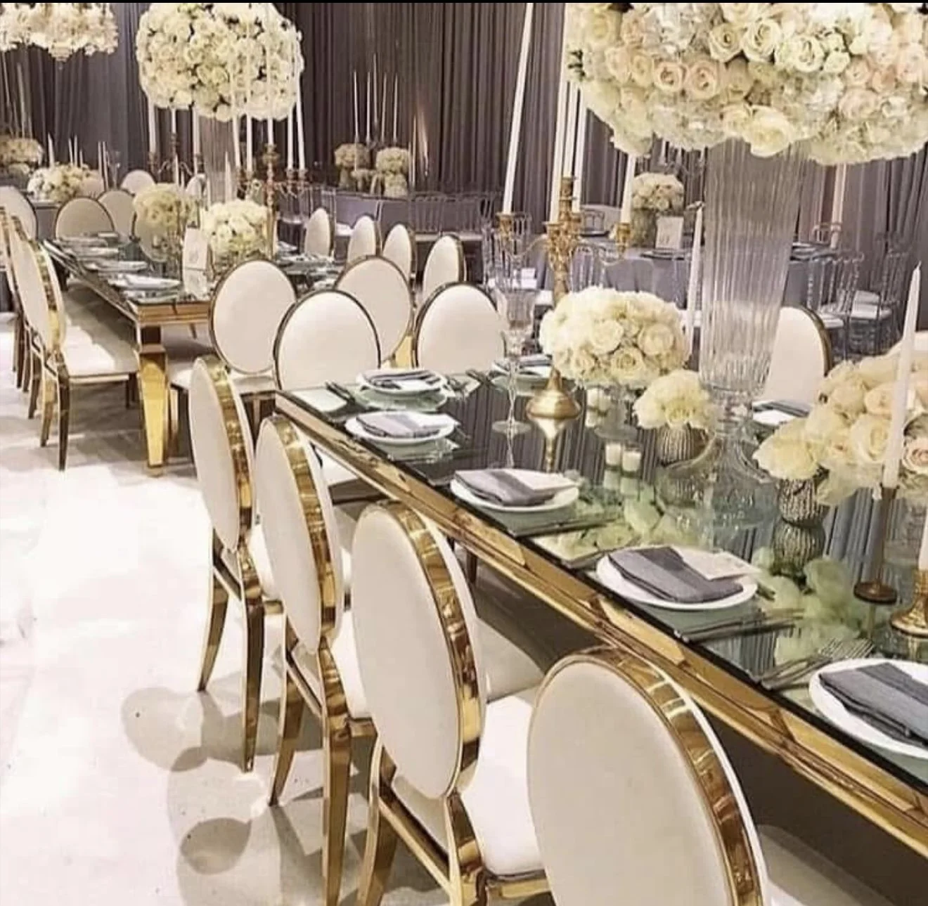 Elegant banquet table decorated with white flowers, tall vases, and candles, set for a formal event or wedding reception.