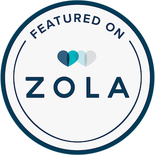 Circular badge with the text 'Featured on Zola' and three overlapping heart icons in shades of blue and grey.