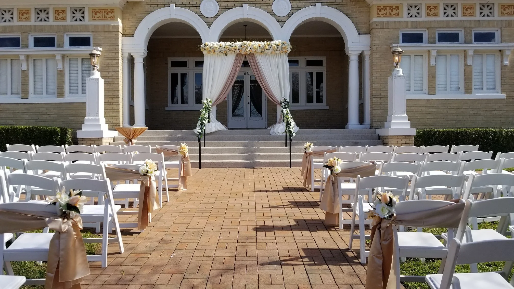 Outdoor Polk County wedding ceremony featuring rental chairs, florals with pipe and draping