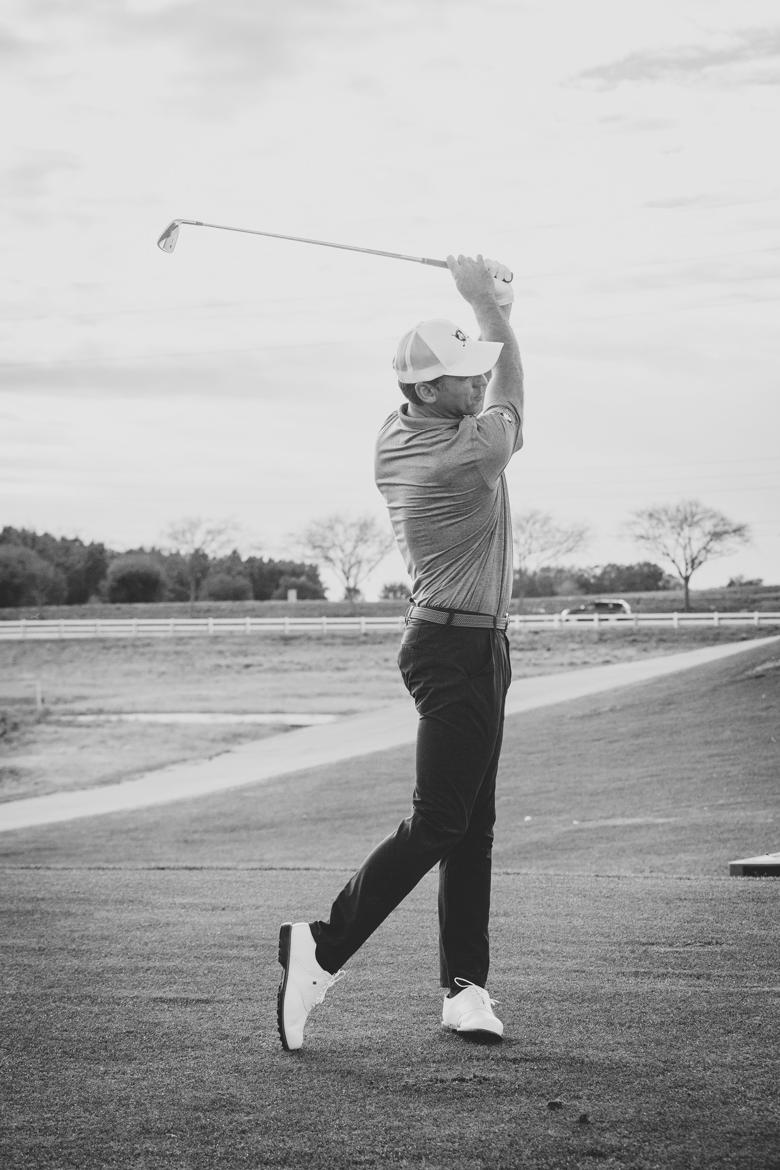 Black and white action sports photography of a man swinging a golf club outdoors