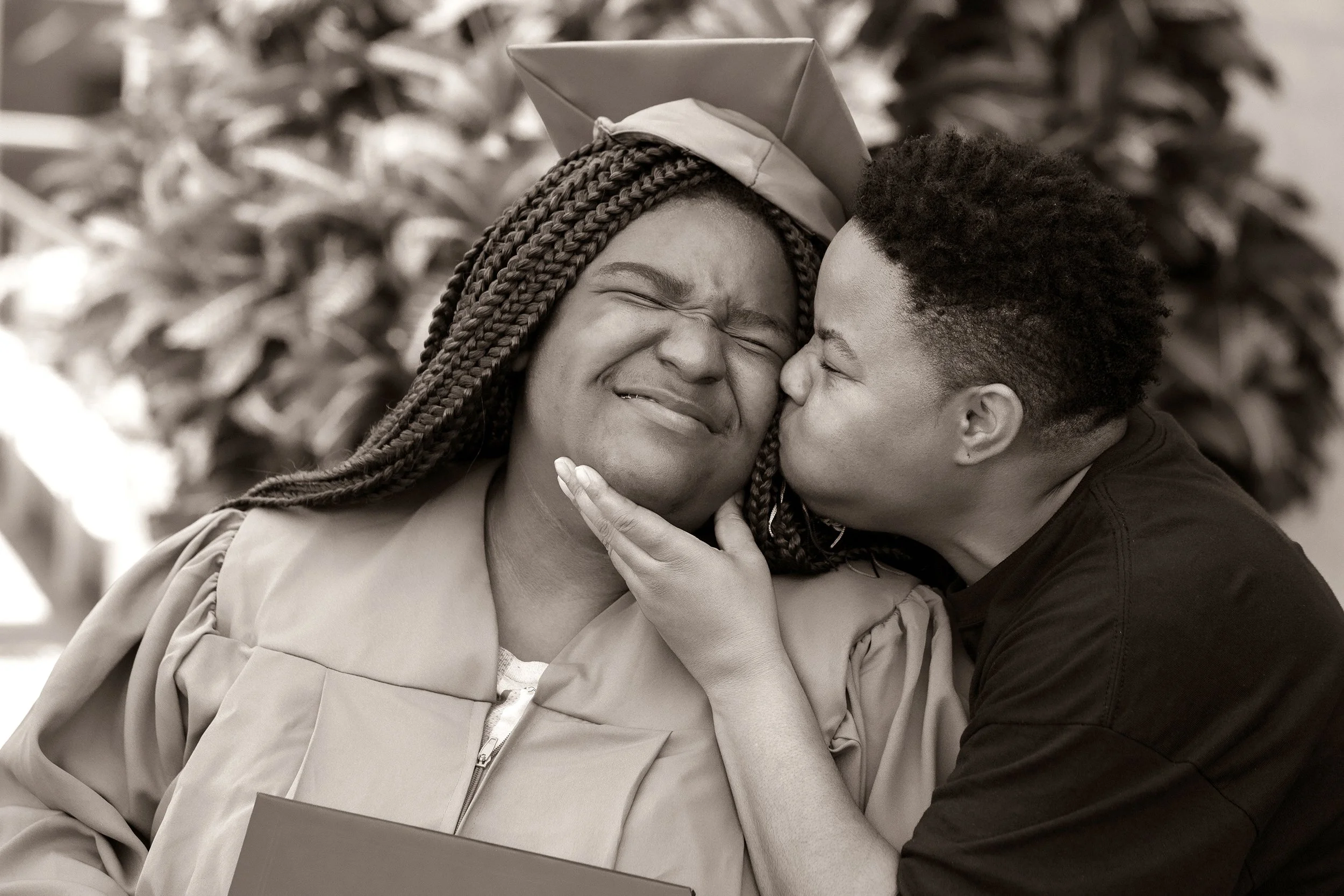 Graduation photography of a smiling senior receiving a celebratory kiss on the cheek, photographed by Lindsay Parks Photography