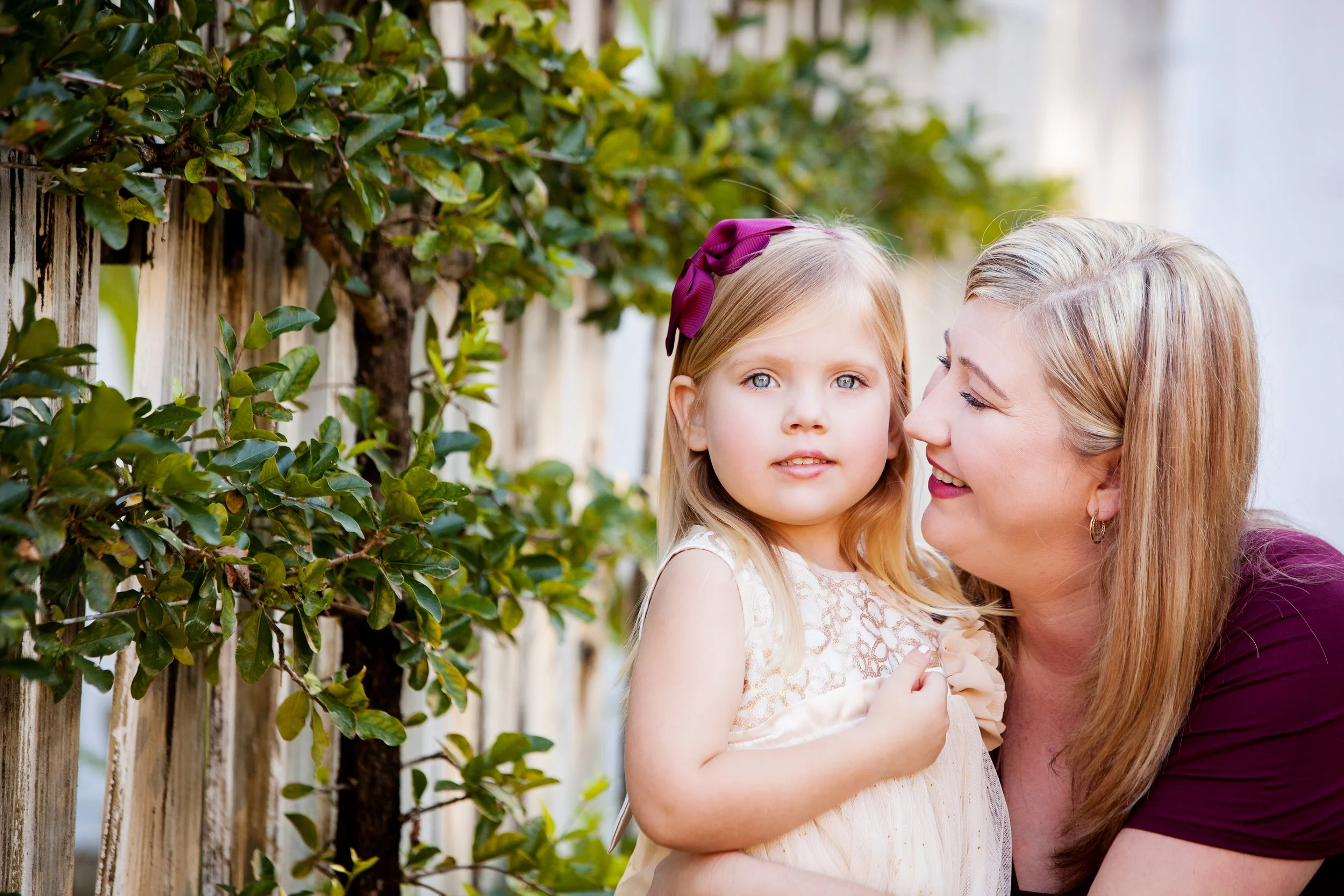 Lifestyle family portrait of a mother holding her daughter near a wooden fence