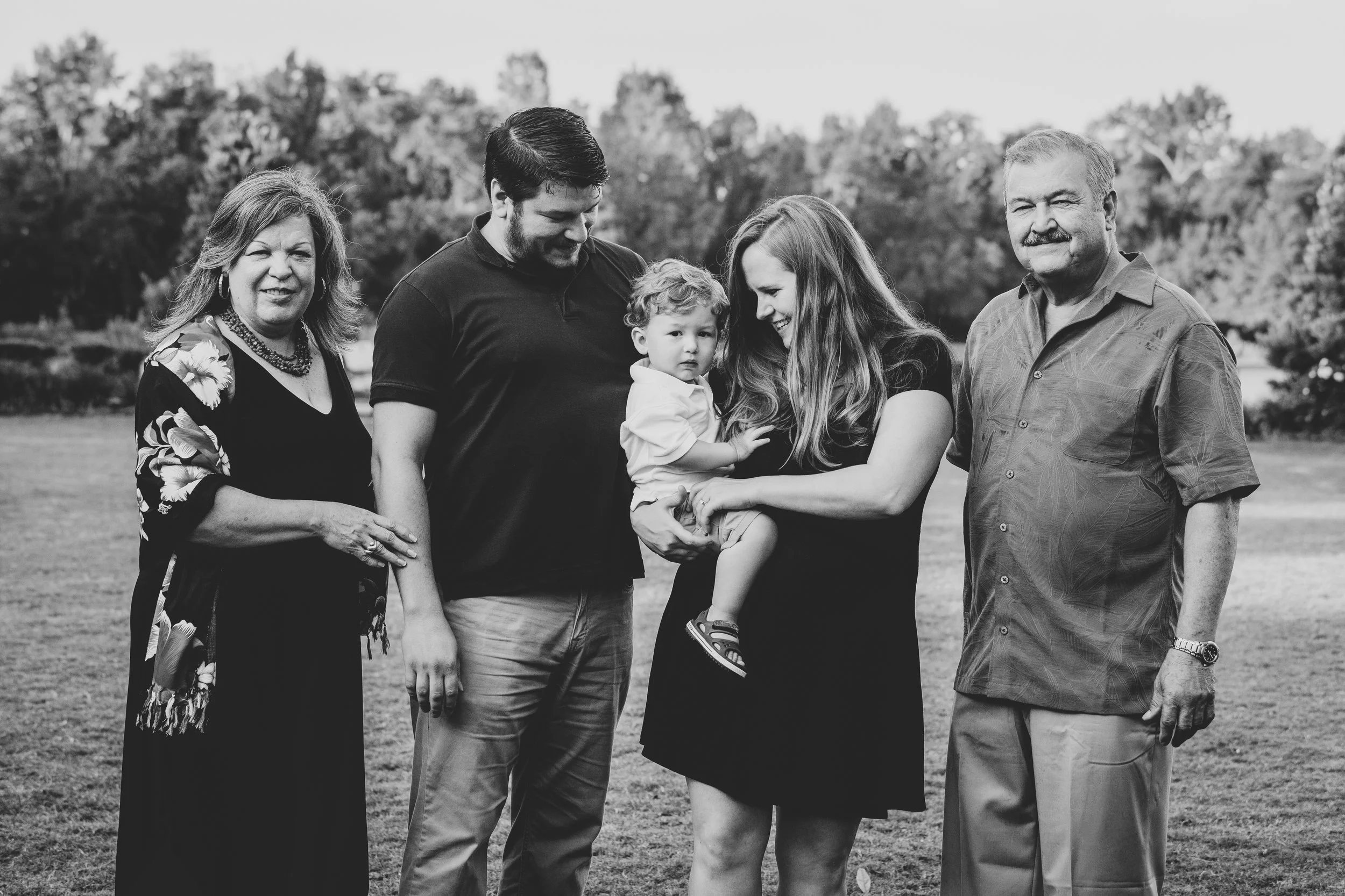 Black and white extended family portrait of five adults and one child standing together outdoors