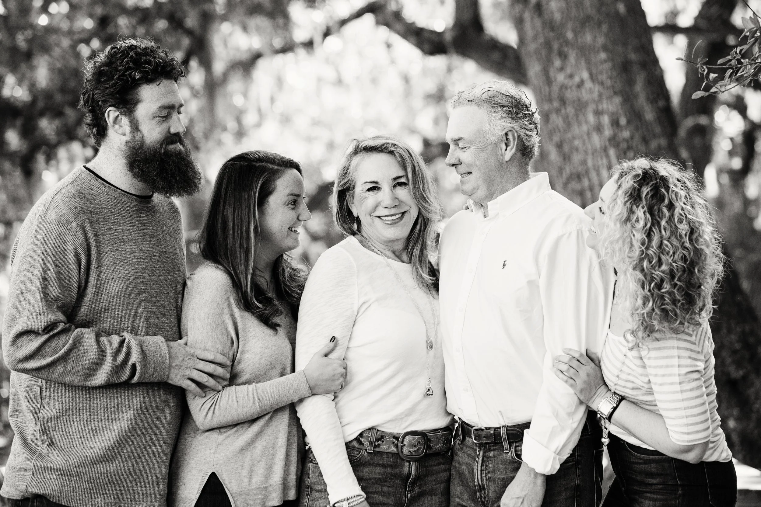Multigenerational extended family  portrait of six adults standing together outdoors beneath a large tree in Florida.
