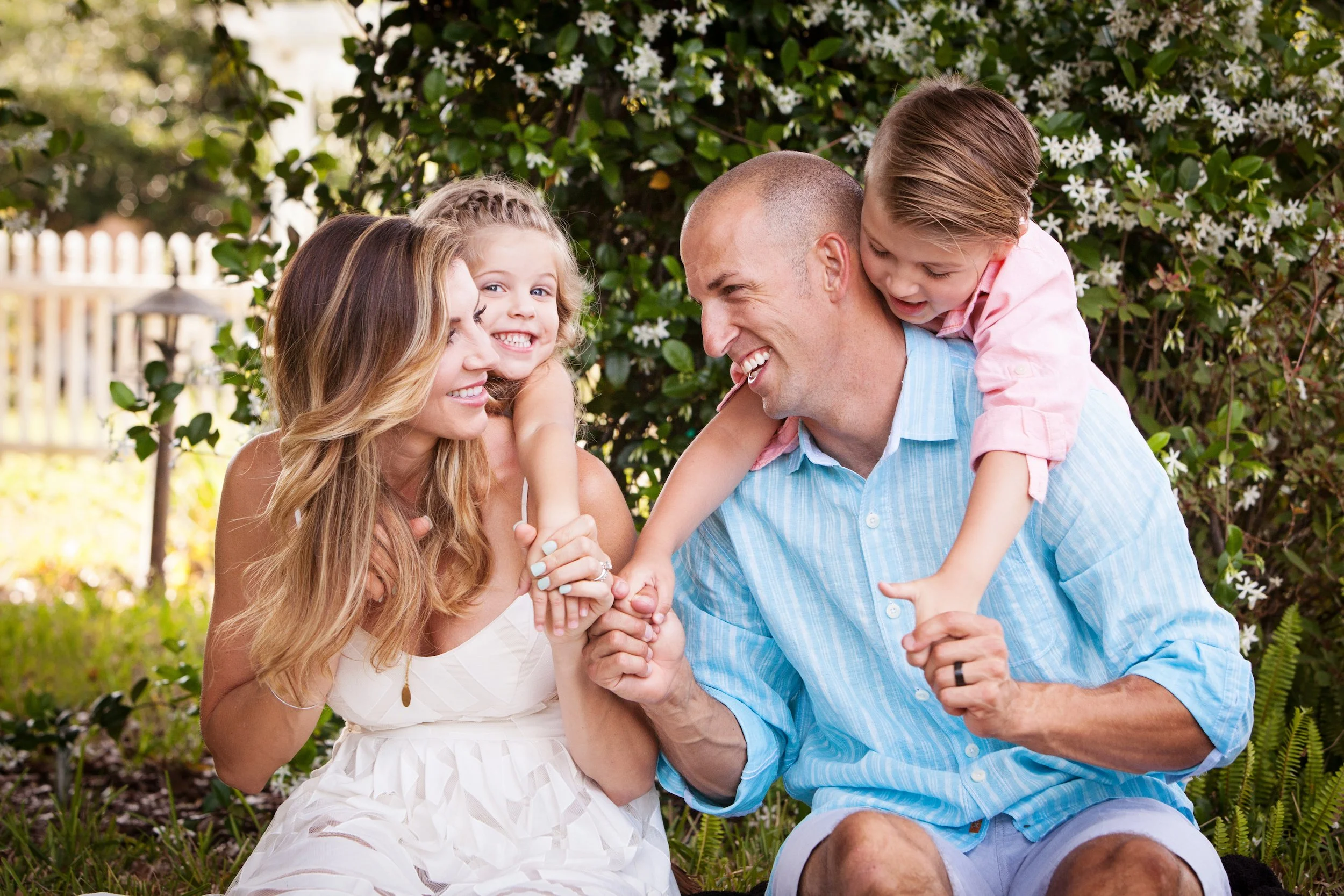 Outdoor family portrait photography session of a family of four playing together among flowers and greenery, photographed by Lindsay Parks Photography.