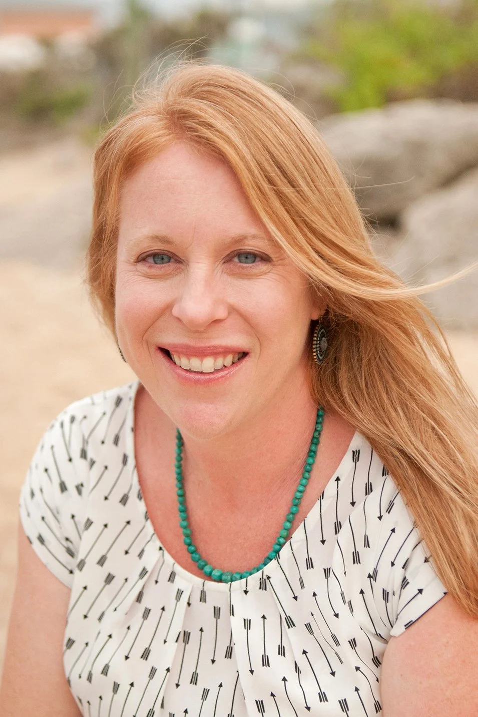 Natural light portrait photo of Lindasy Parks smiling outdoors with a soft, blurred background.