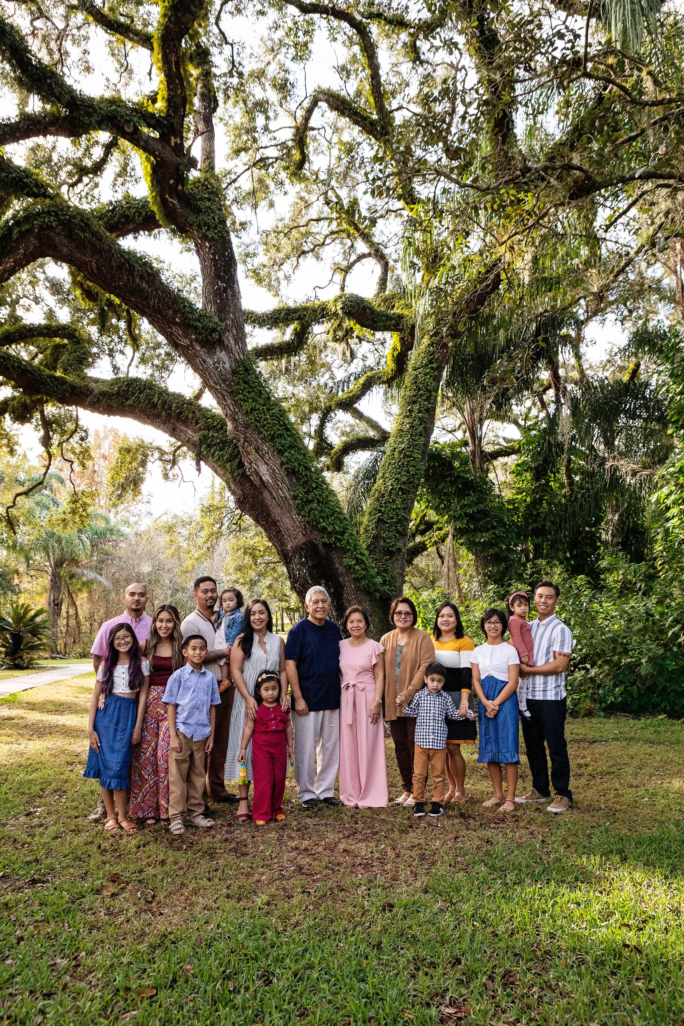 Extended family photography of a large group gathered beneath a moss-covered tree in a Florida park