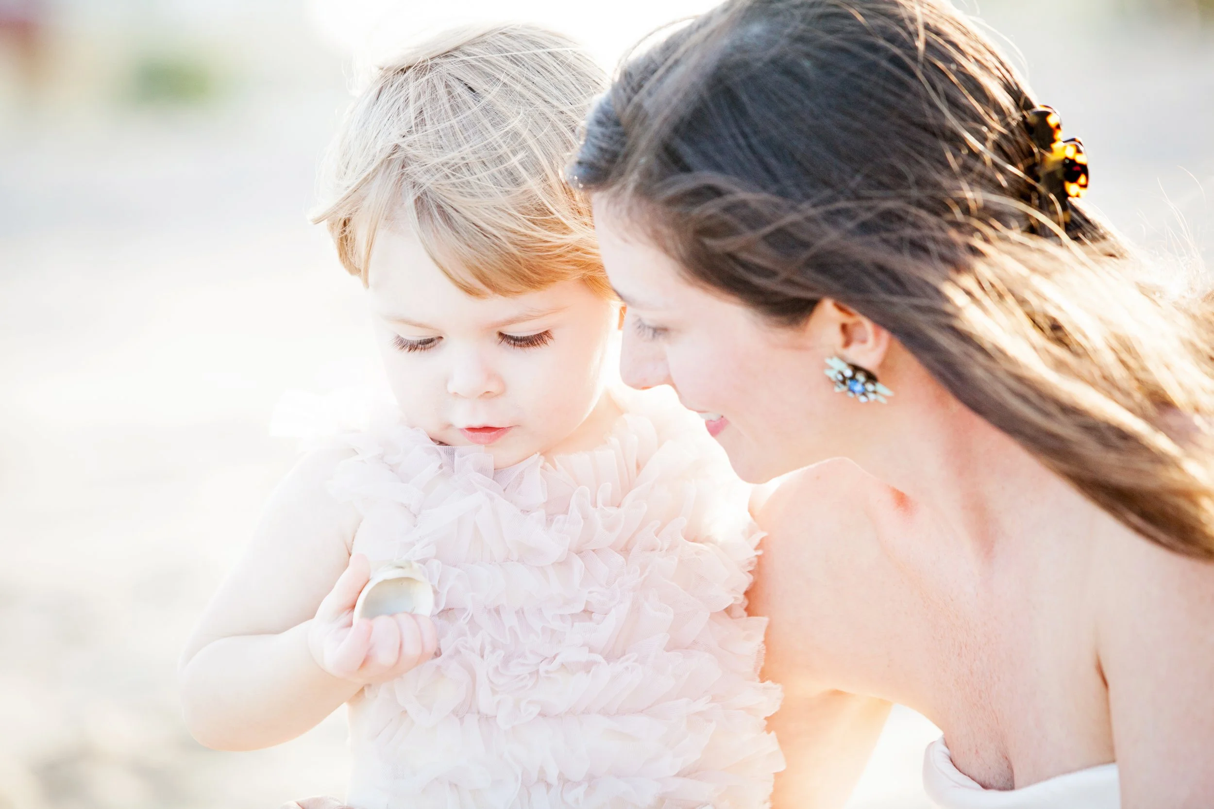 Lifestyle family photography of a mother and daughter examining a seashell outdoors