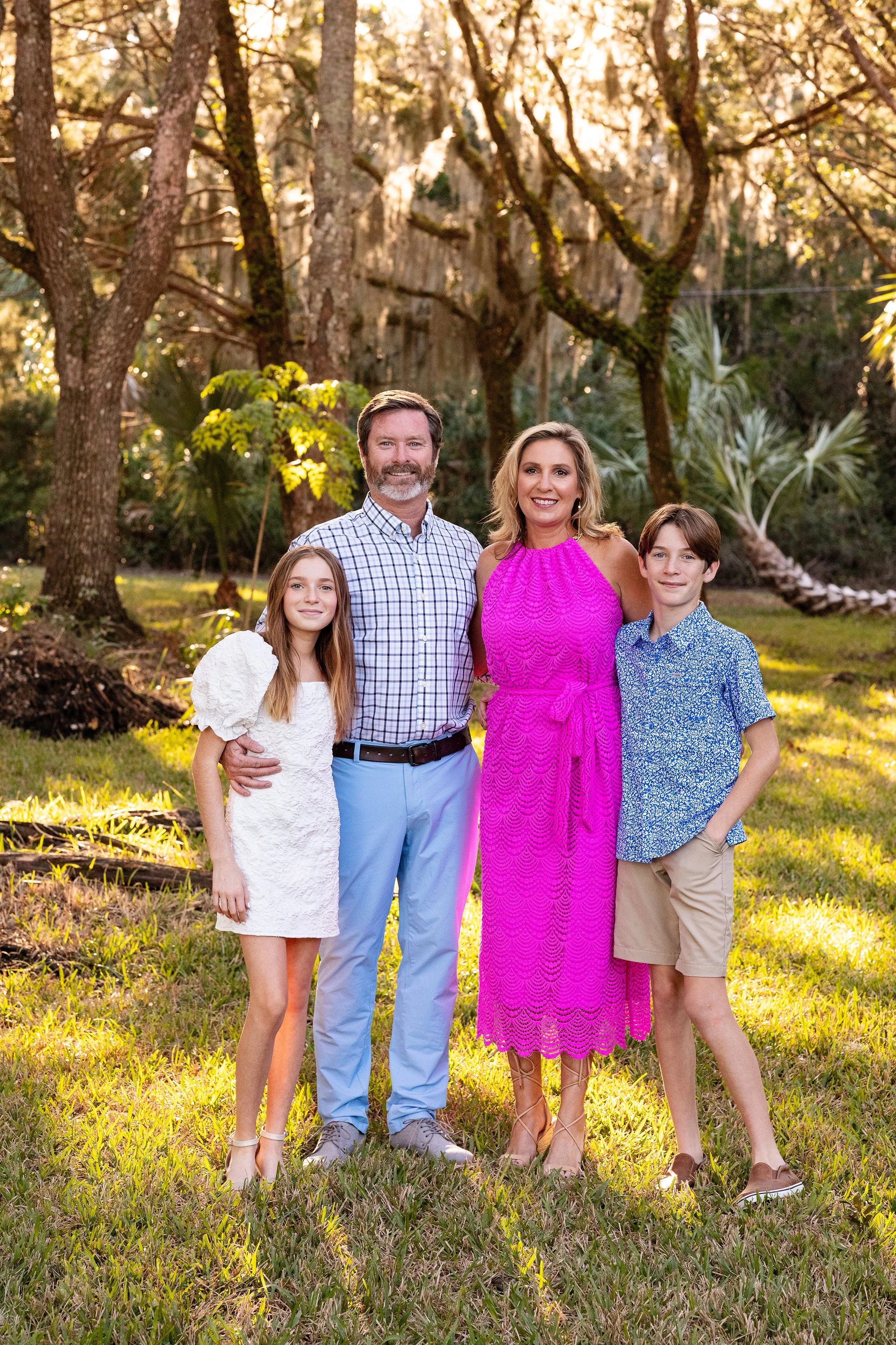 Outdoor family photography of a family of four standing together during golden hour in a park in Florida.