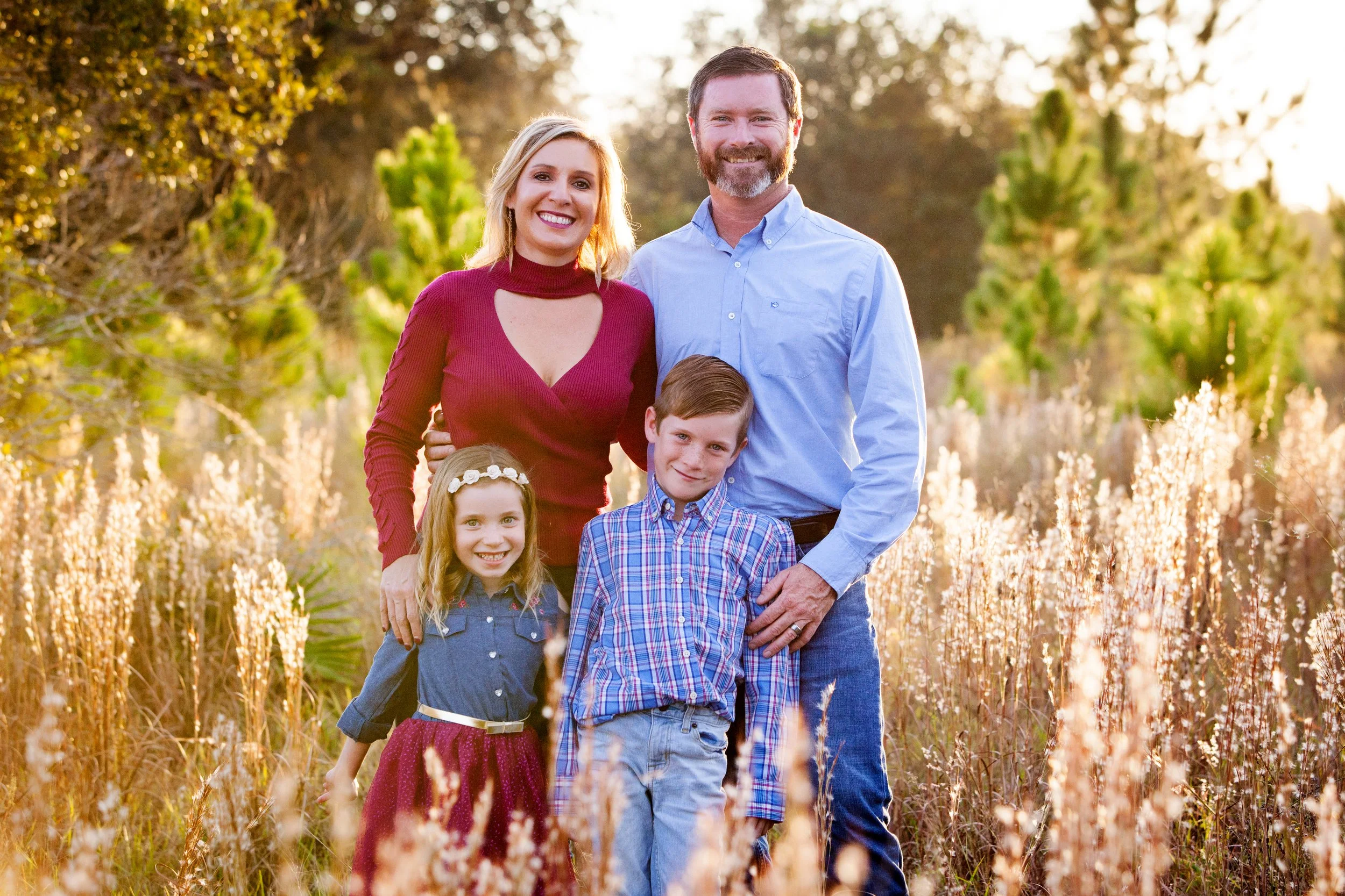 Golden hour family photography of a family of five standing together in a field at sunset