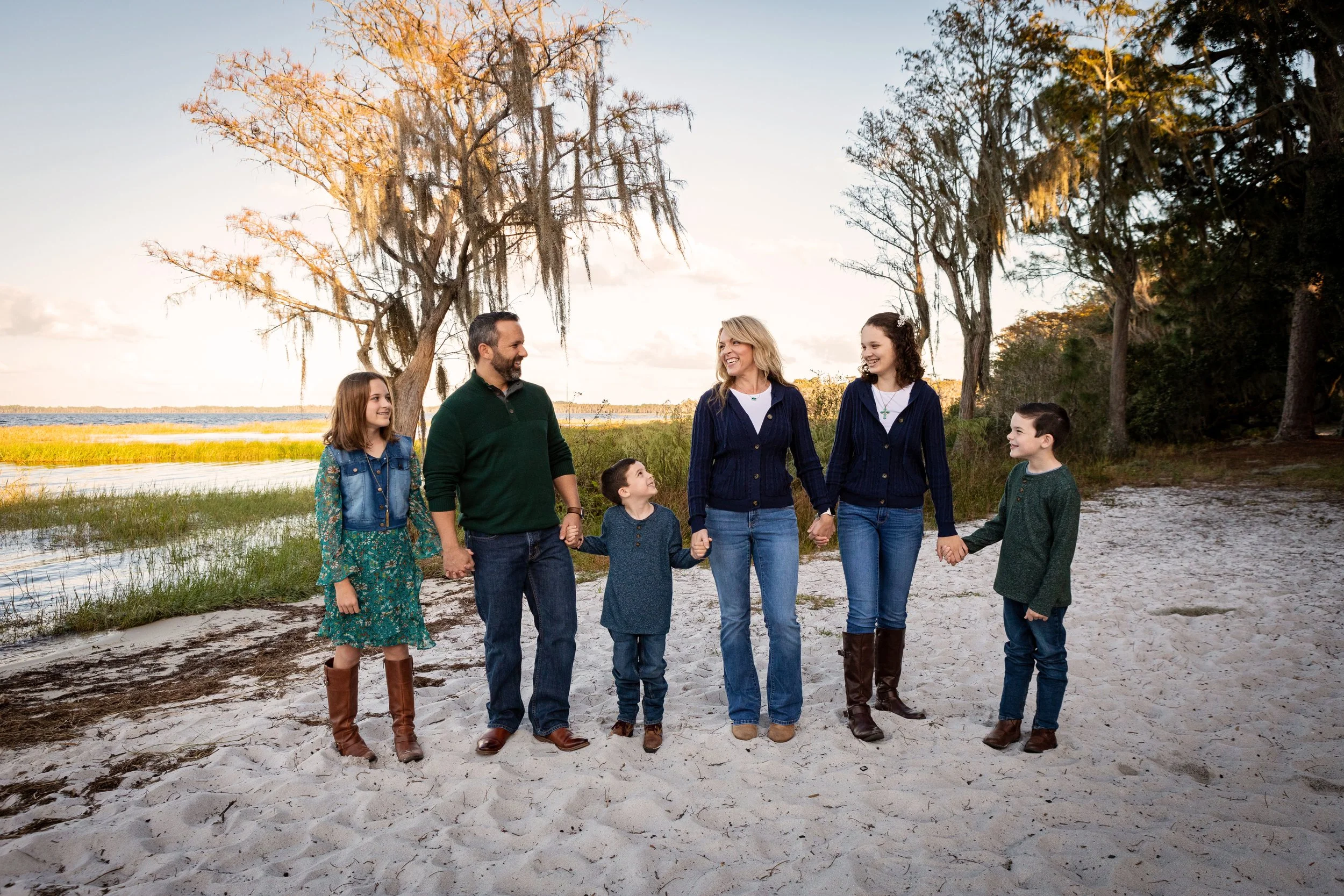 Extended family beach photography of a family of seven holding hands during sunset