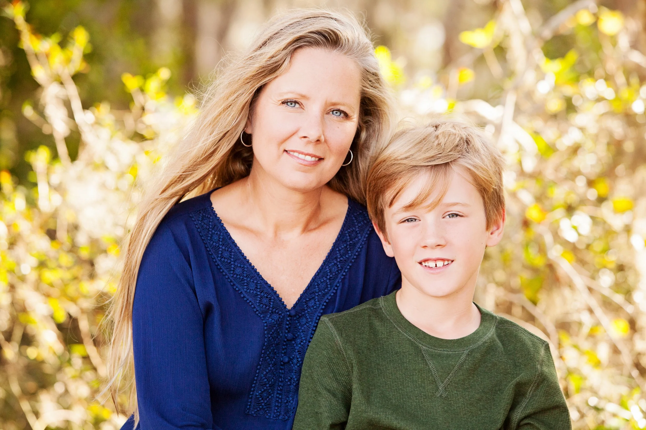 Lifestyle portrait of a mother and son smiling together outdoors in soft natural light
