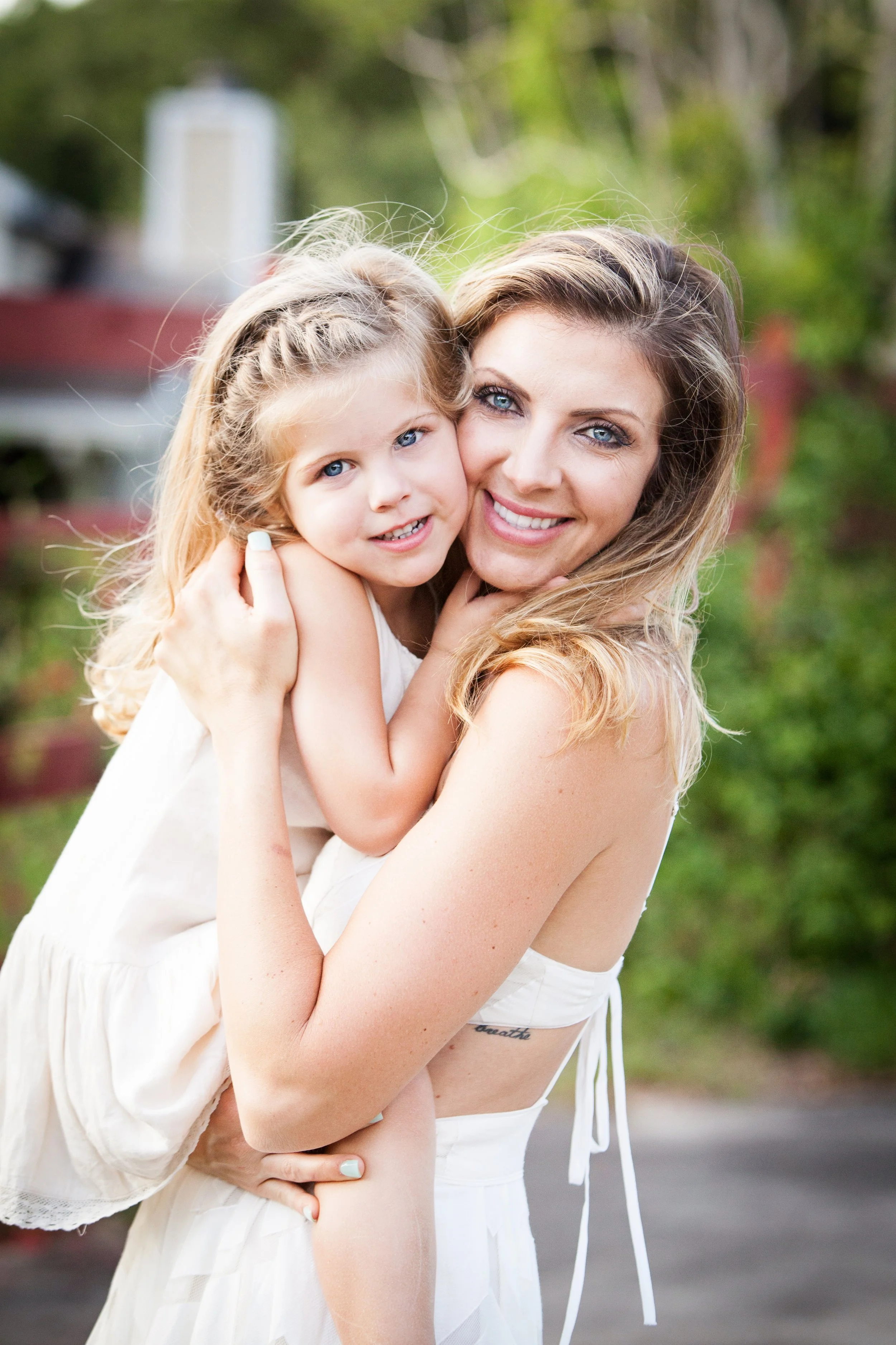 Outdoor family photography of a mother hugging her young daughter surrounded by greenery