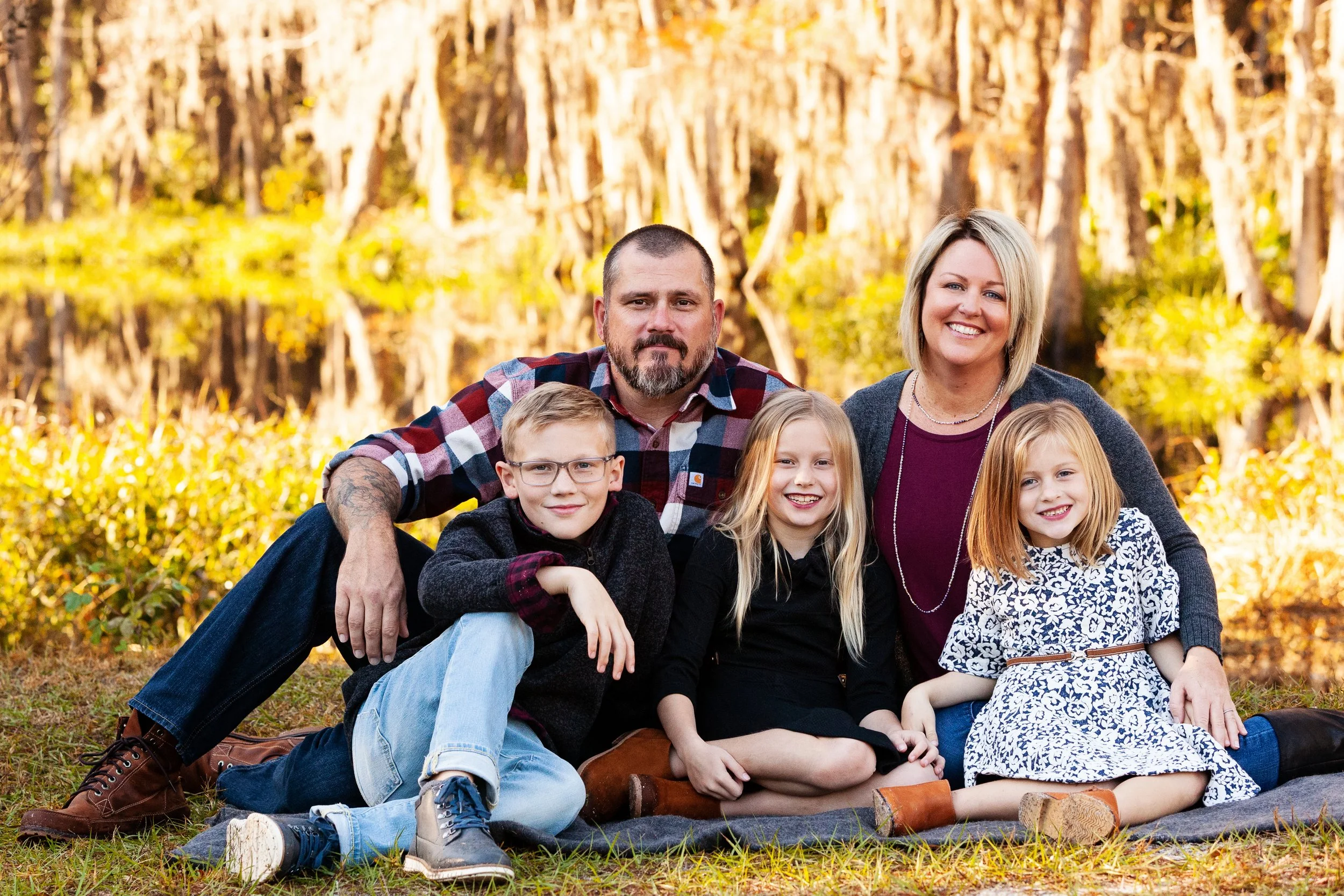 Fall family photography of a family of five sitting on a blanket surrounded by autumn leaves