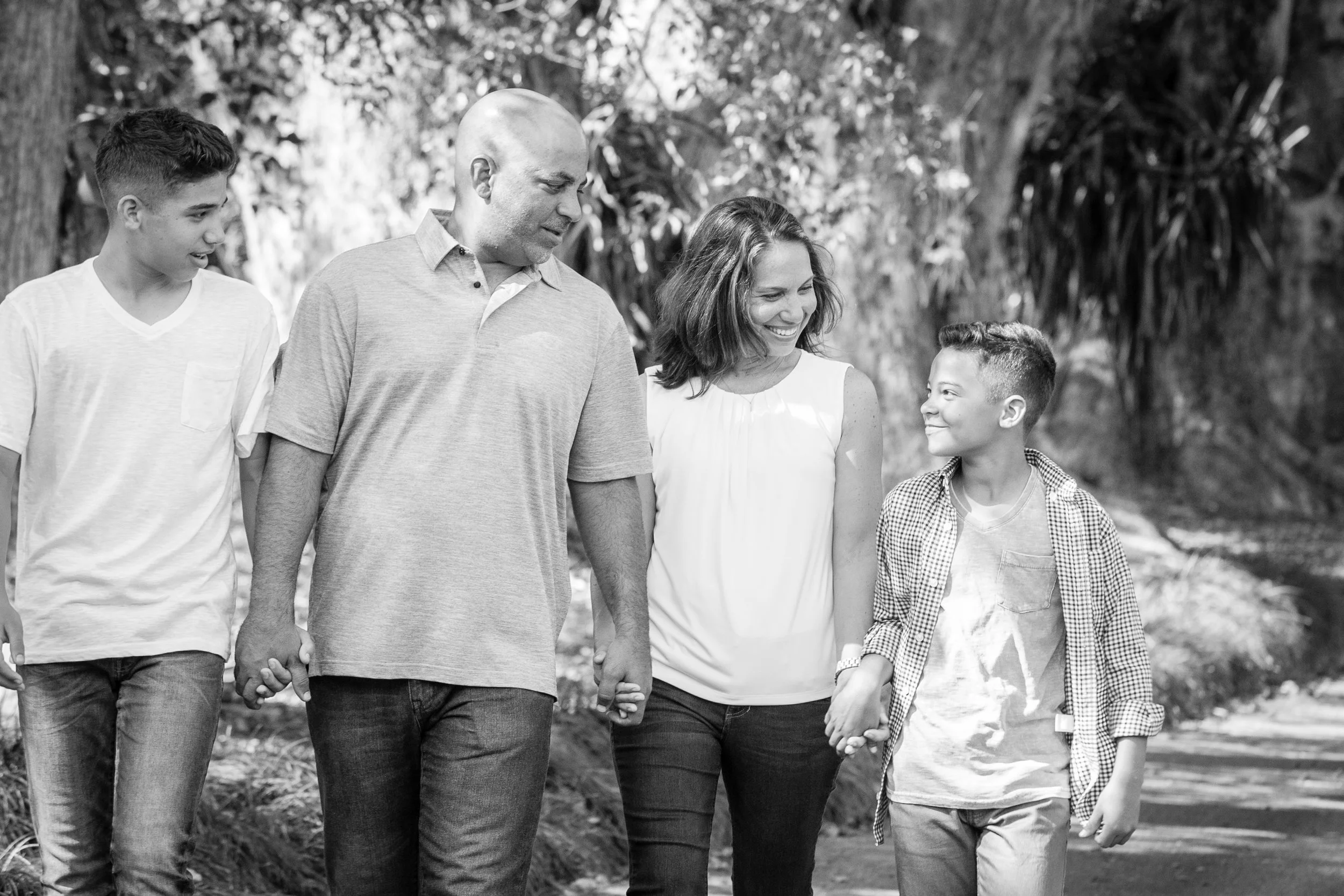 Outdoor family photography of a family of five walking hand-in-hand through a park