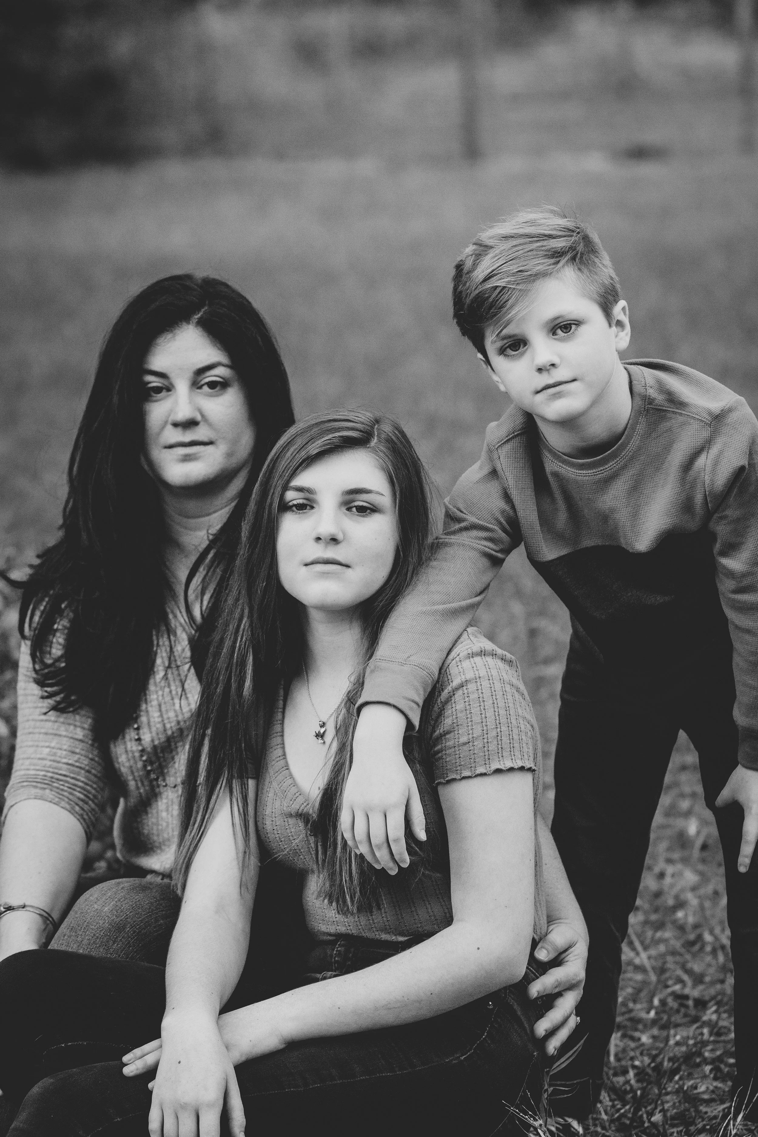 Black and white lifestyle family portrait of a woman, teenage girl, and young boy outdoors