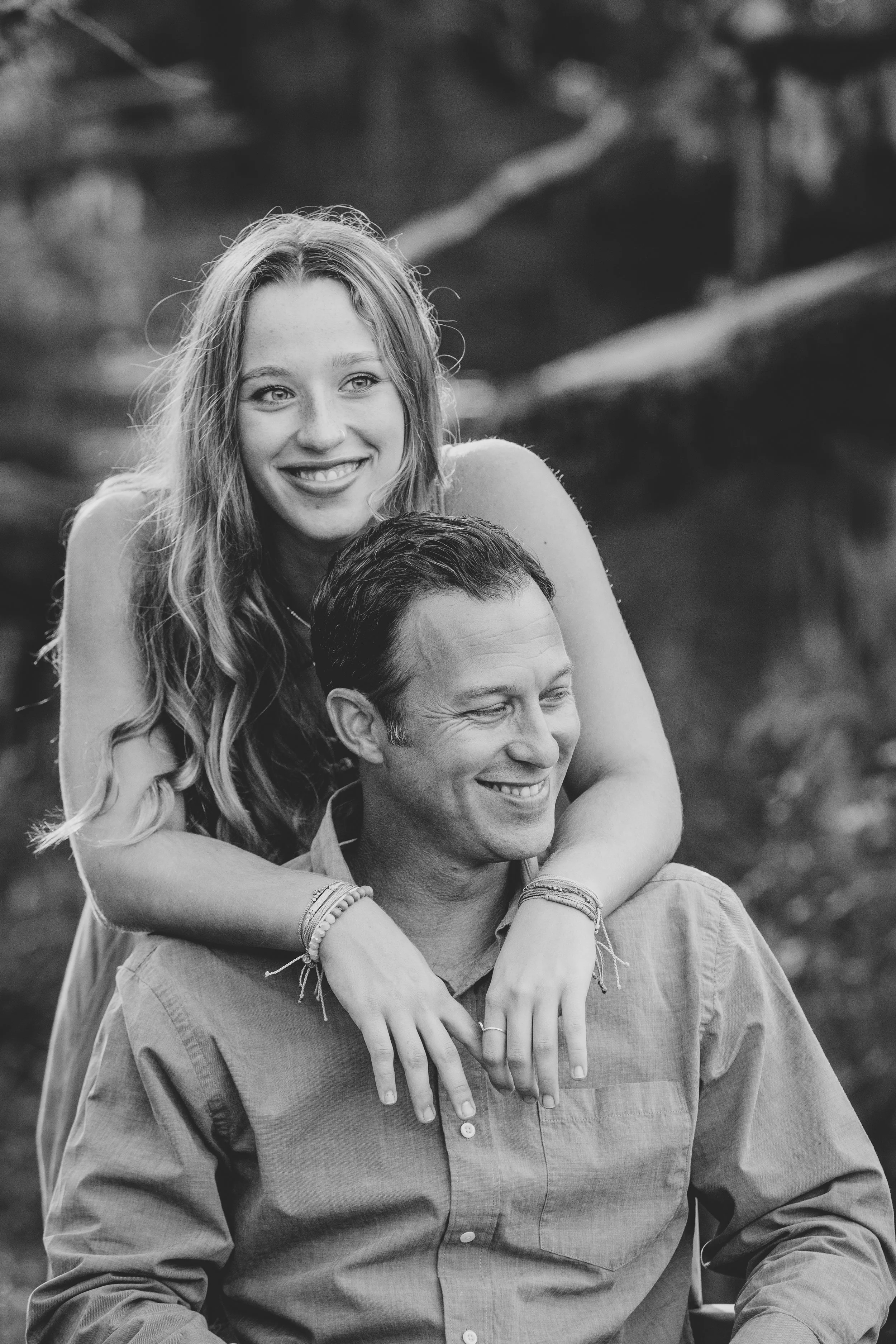 Black and white lifestyle portrait of a smiling couple leaning into each other outdoors