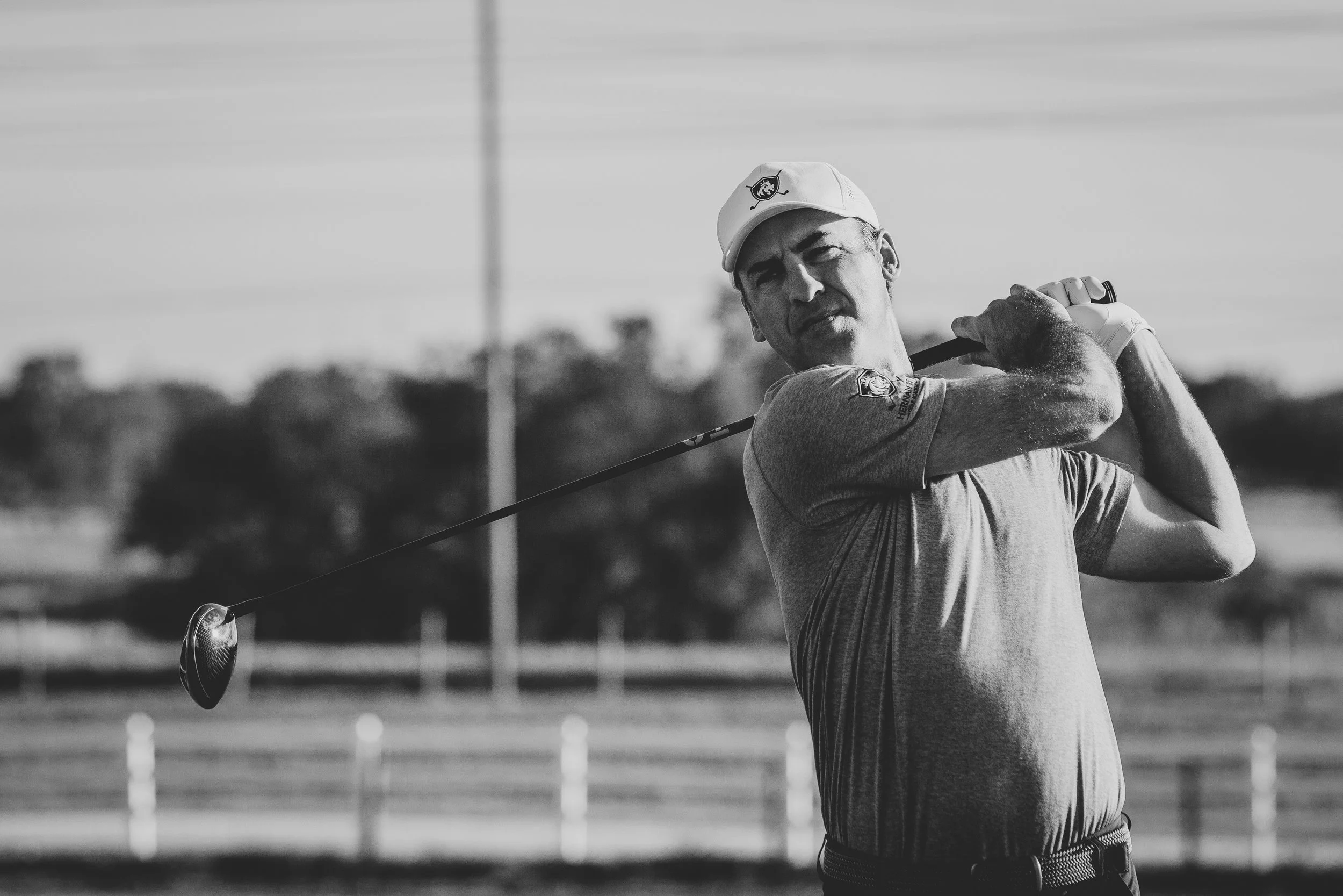 Black and white sports photography of a man mid-swing on a golf course 