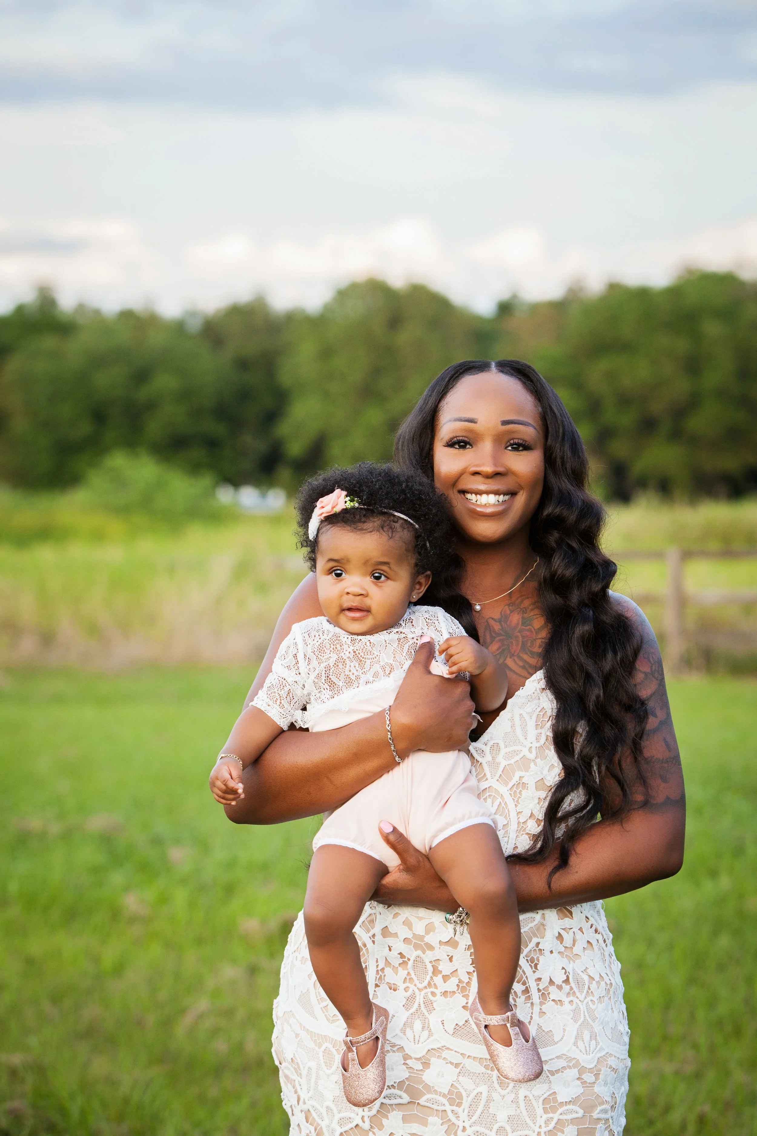Lifestyle family portrait of a mother holding her daughter in an open grassy field