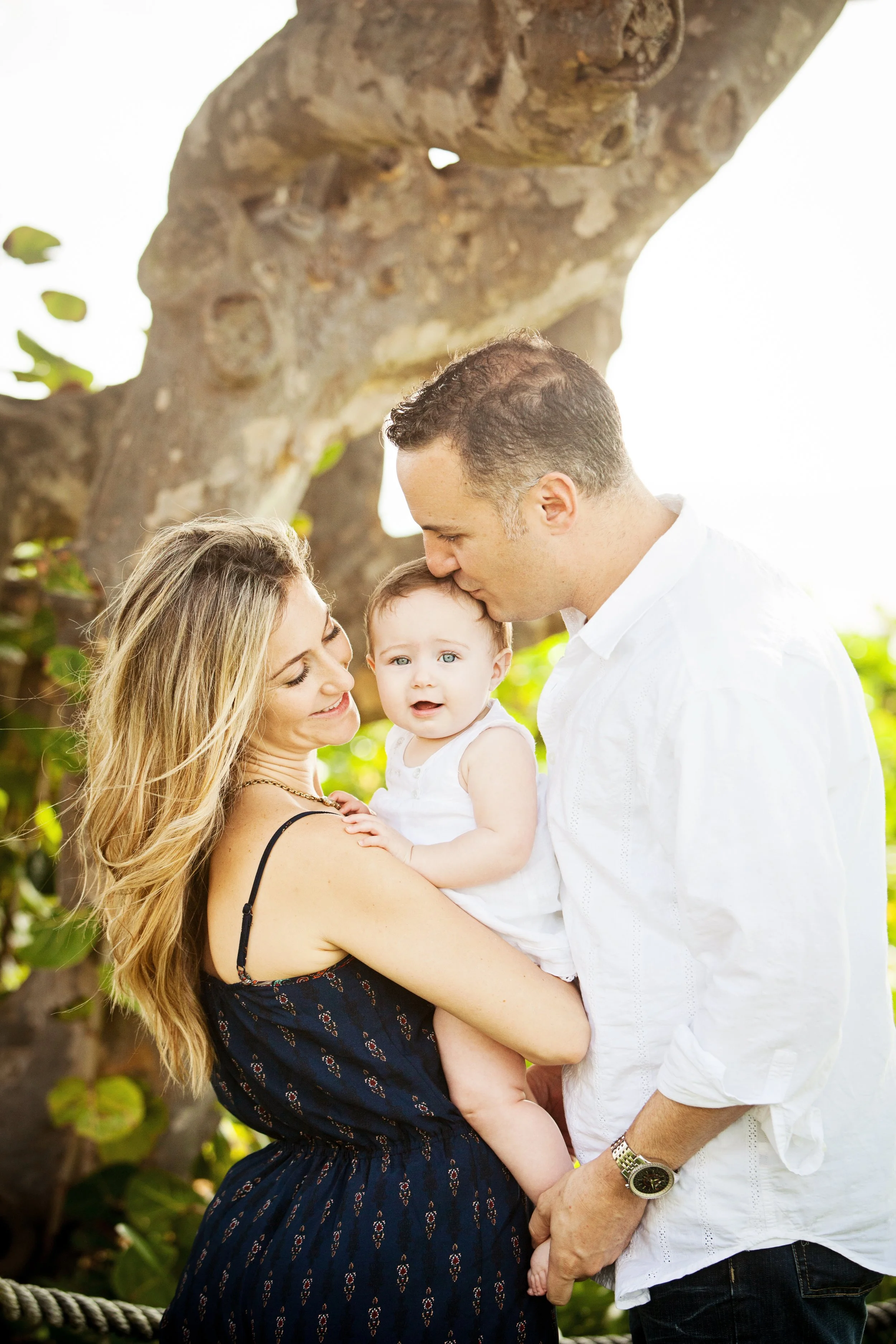 Lifestyle newborn family portrait of parents sharing a tender moment with their baby outdoors