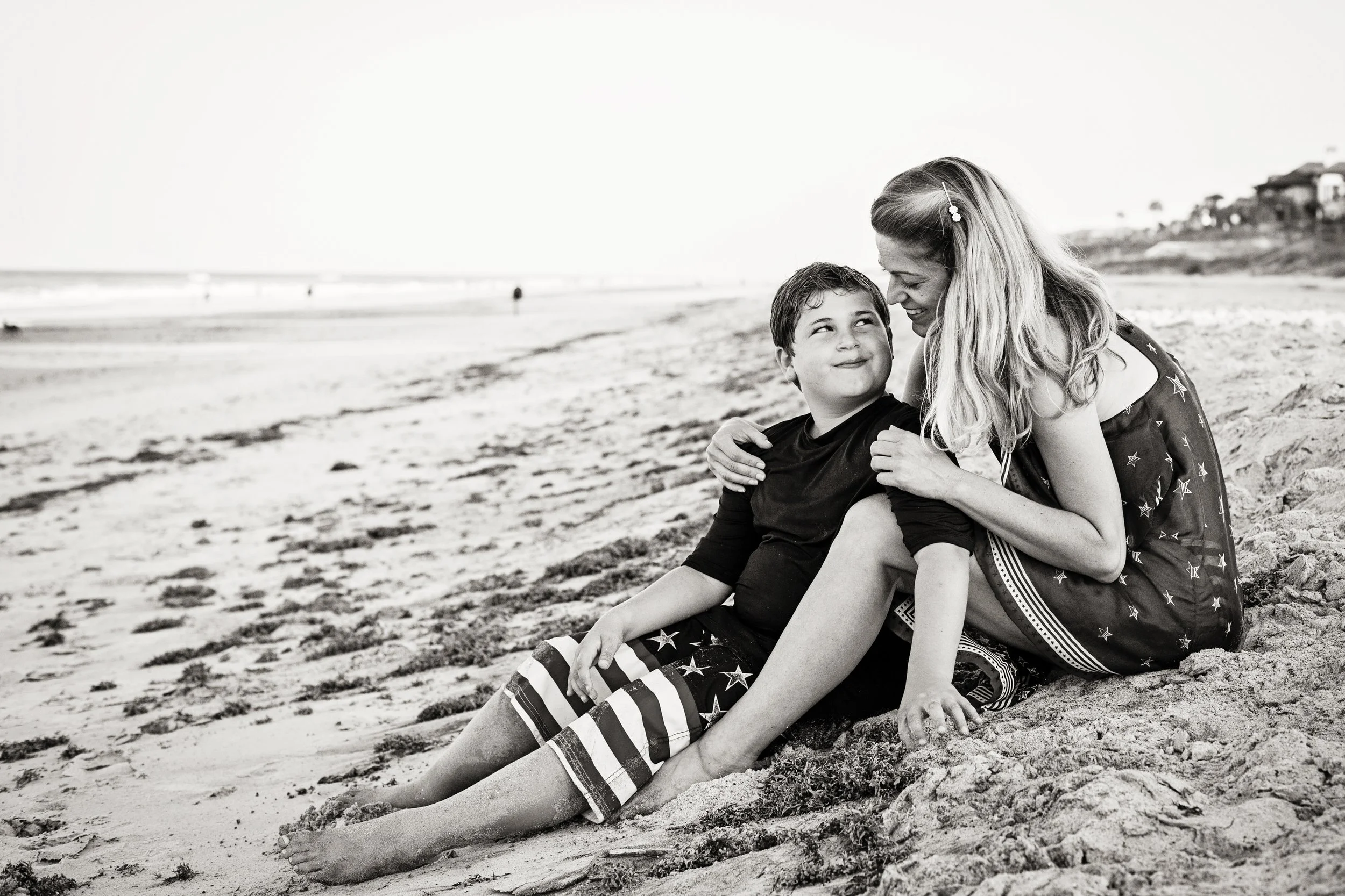 Beach family portrait of a mother and son sitting together near the shoreline