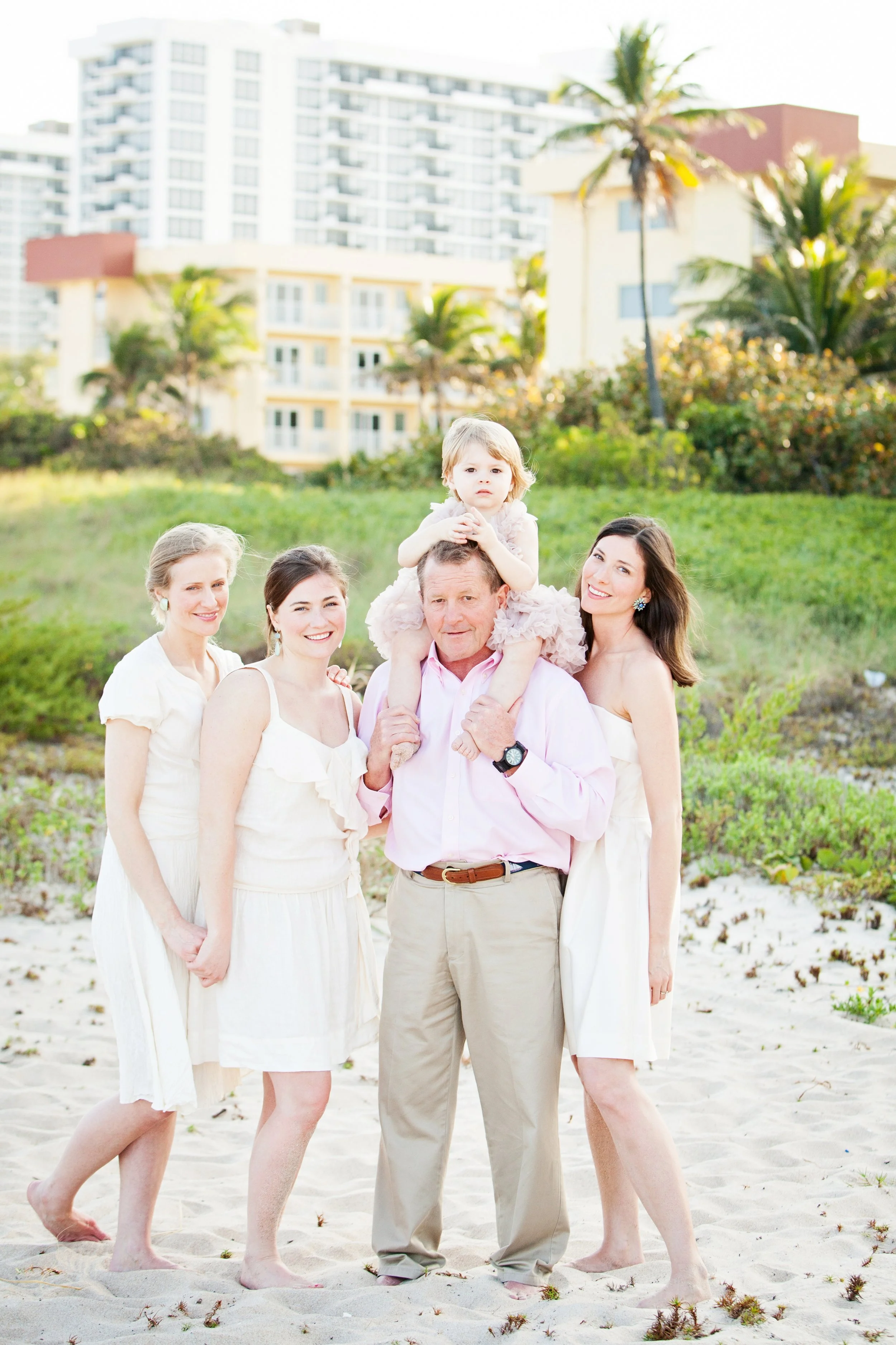 Florida beach family photography of a family of five posing near sand and palm trees highlighted by natural light. 