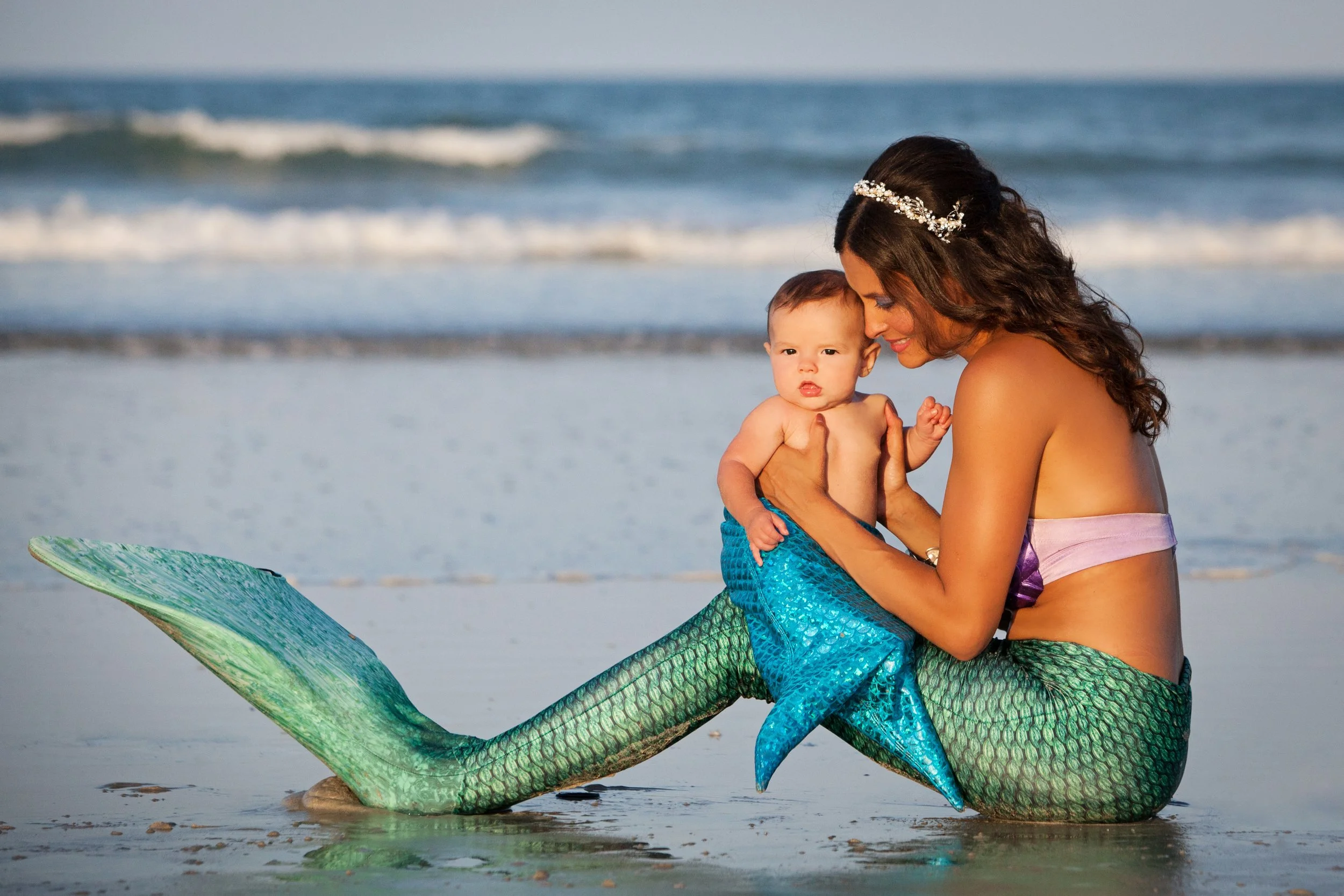 Creative lifestyle portrait photography by Lindsay Parks of a woman dressed as a mermaid holding a baby on a Florida beach