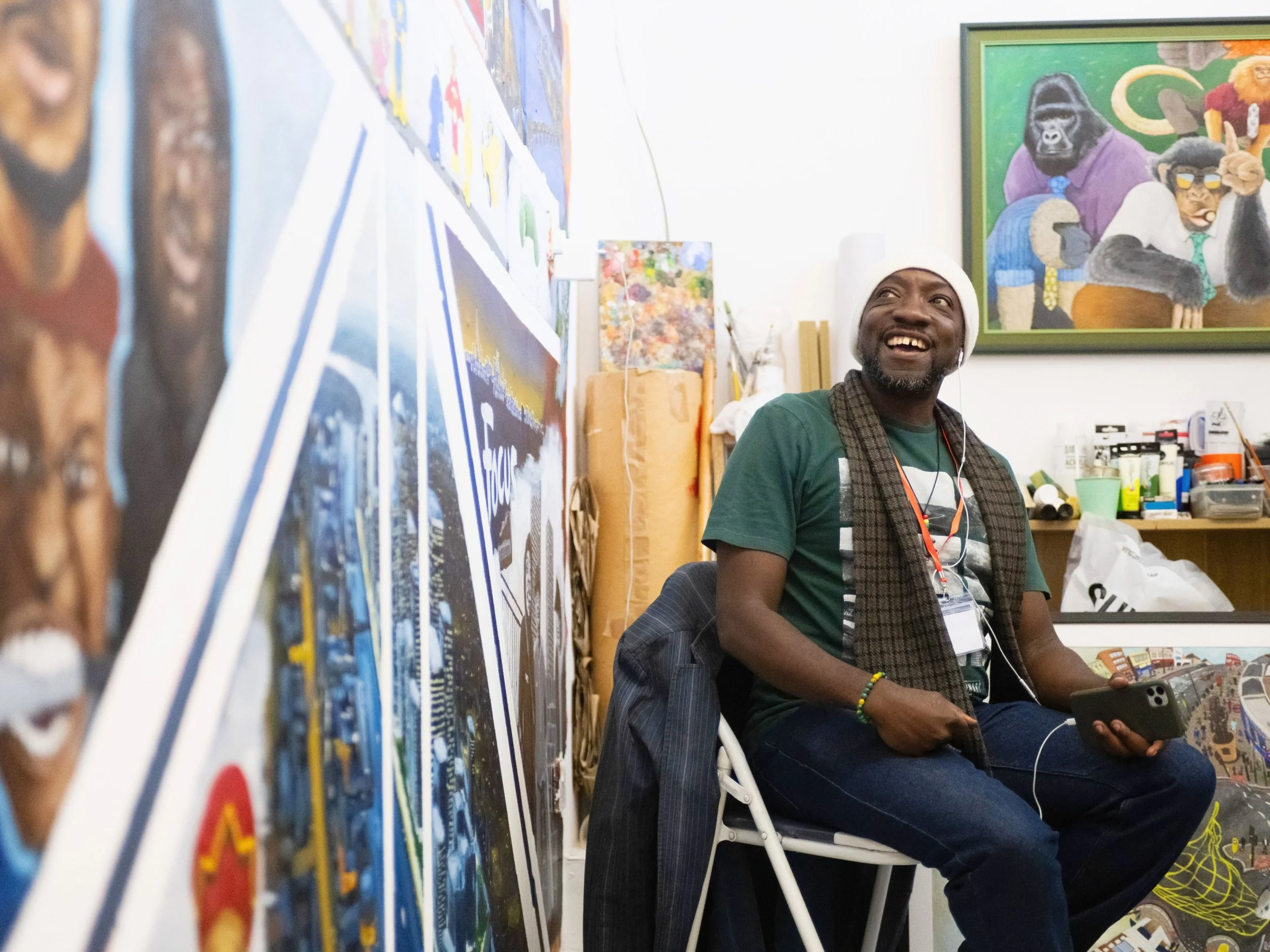 Inside of one of the Green art studios, with the resident artist from the space smiling at the painted mural he has inside his creative space. In the background, there are art materials.