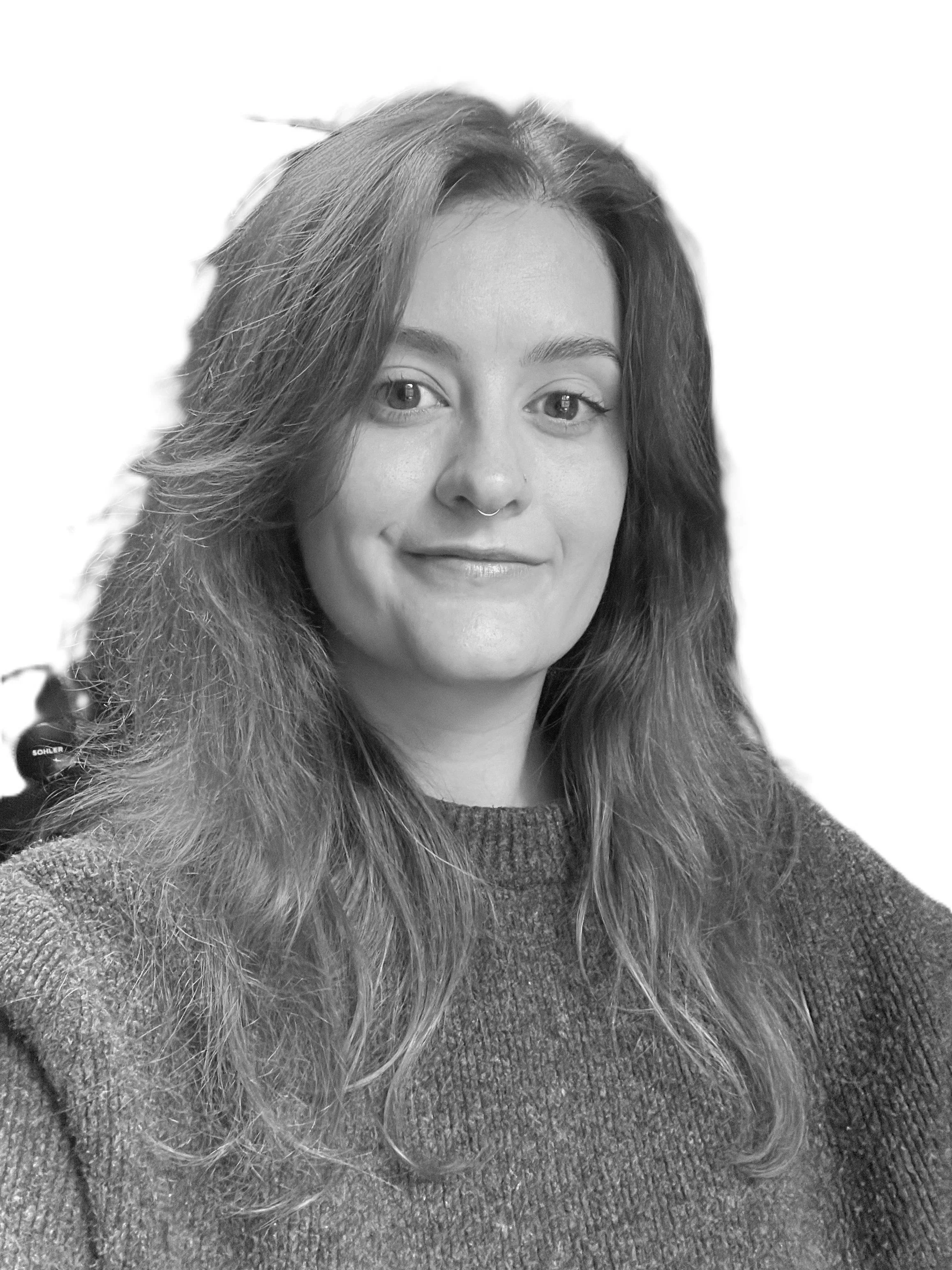 A smiling woman with curly hair forming a heart shape with her hands.