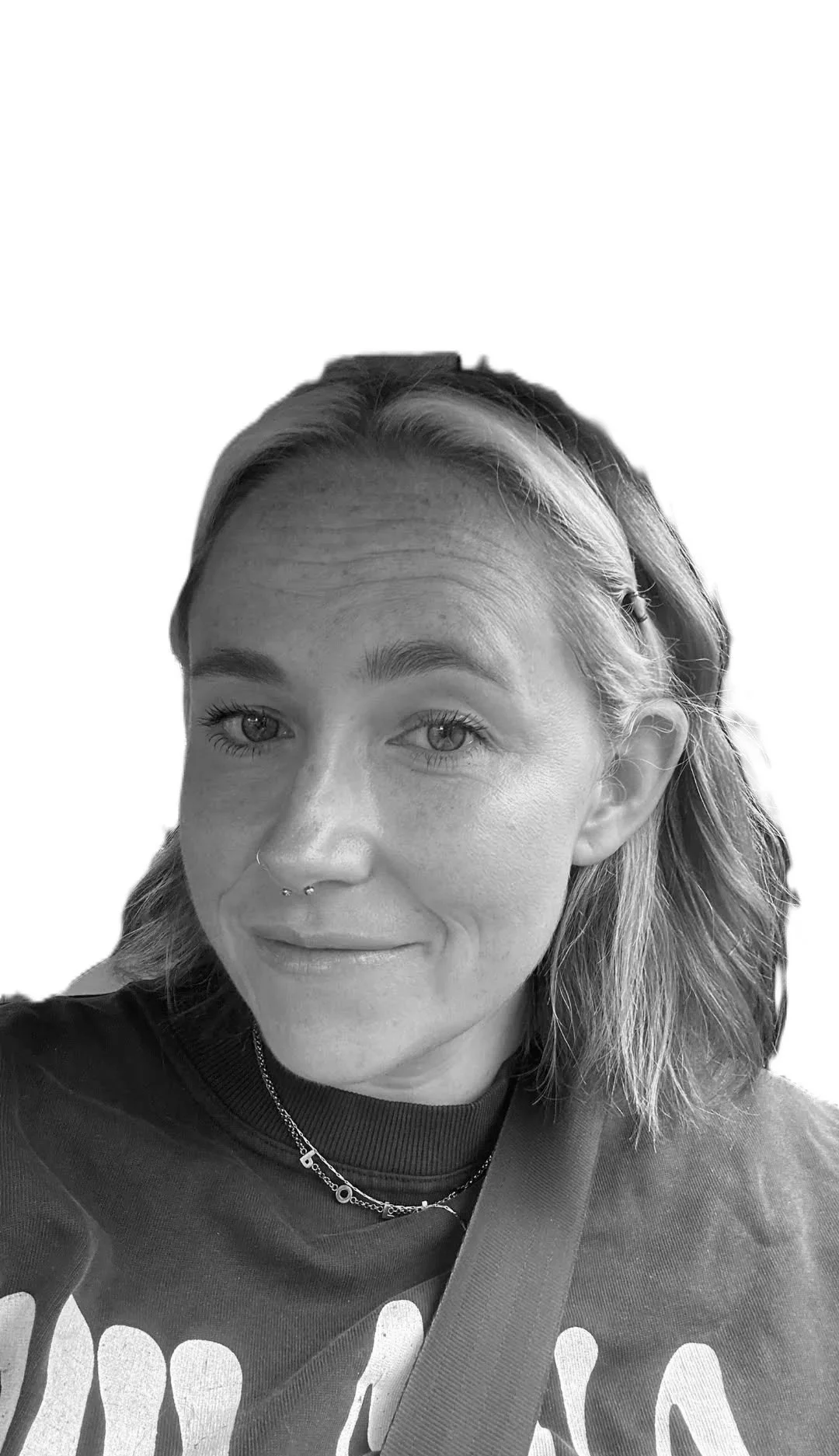 A smiling woman makes a heart shape with her hands around her face, wearing a black top with lace details, jewelry, and a watch, in black and white photo.