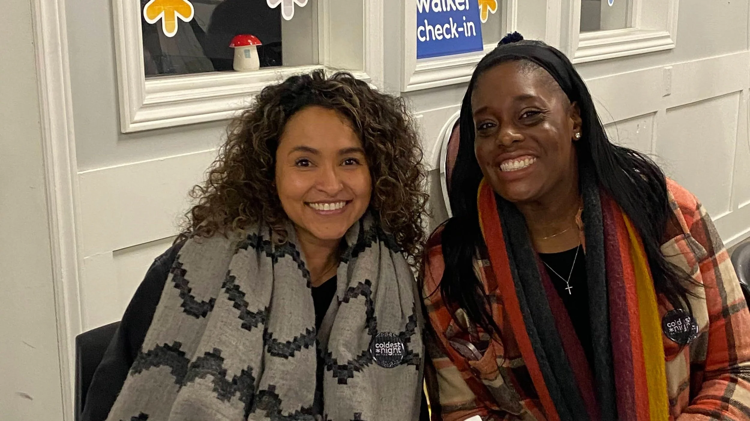 Two volunteers at the Coldest Night of the Year Fundraiser smile at the registration table